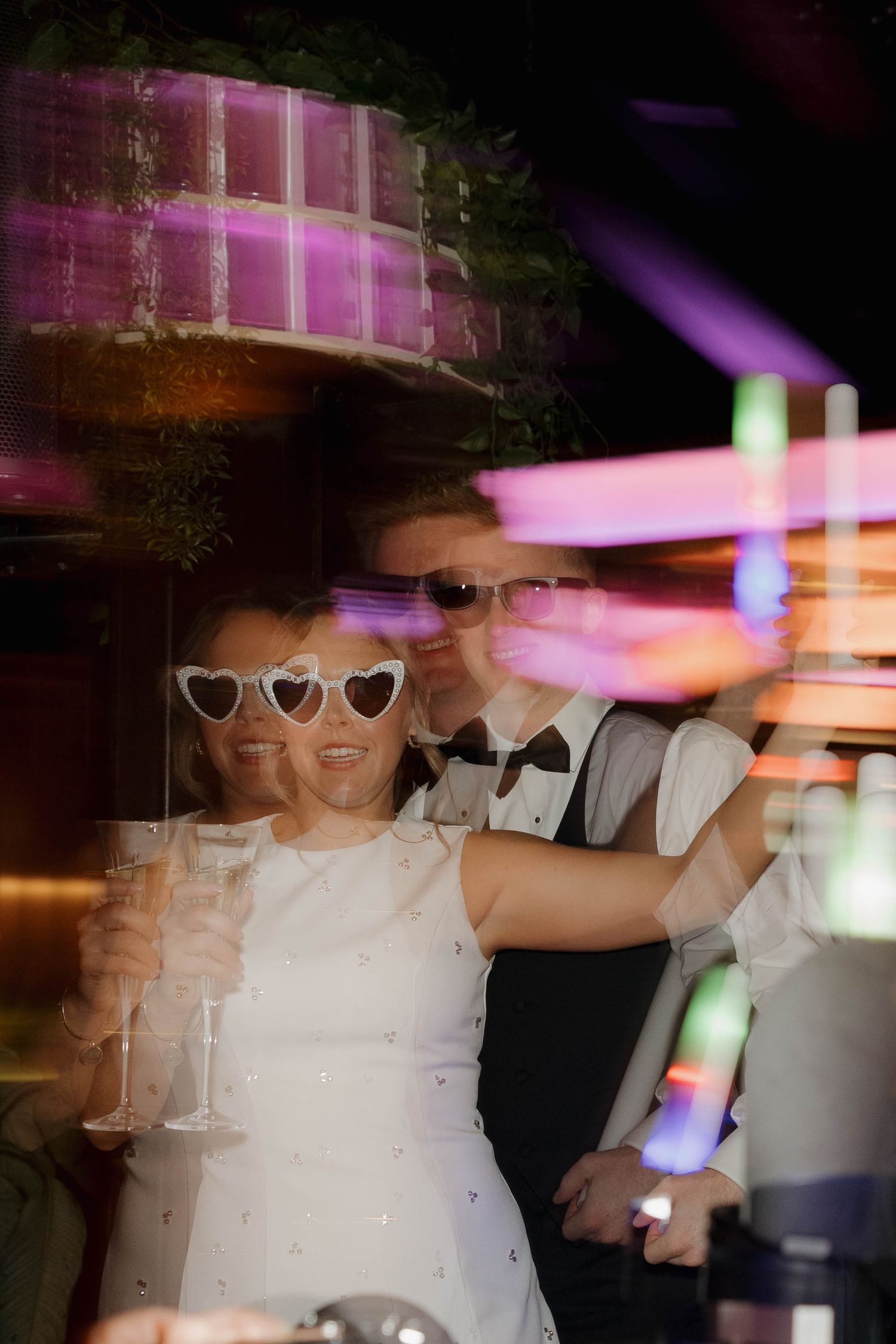 Motion-blurred dance floor photos show a person in white dress with heart sunglasses under colorful party lights.