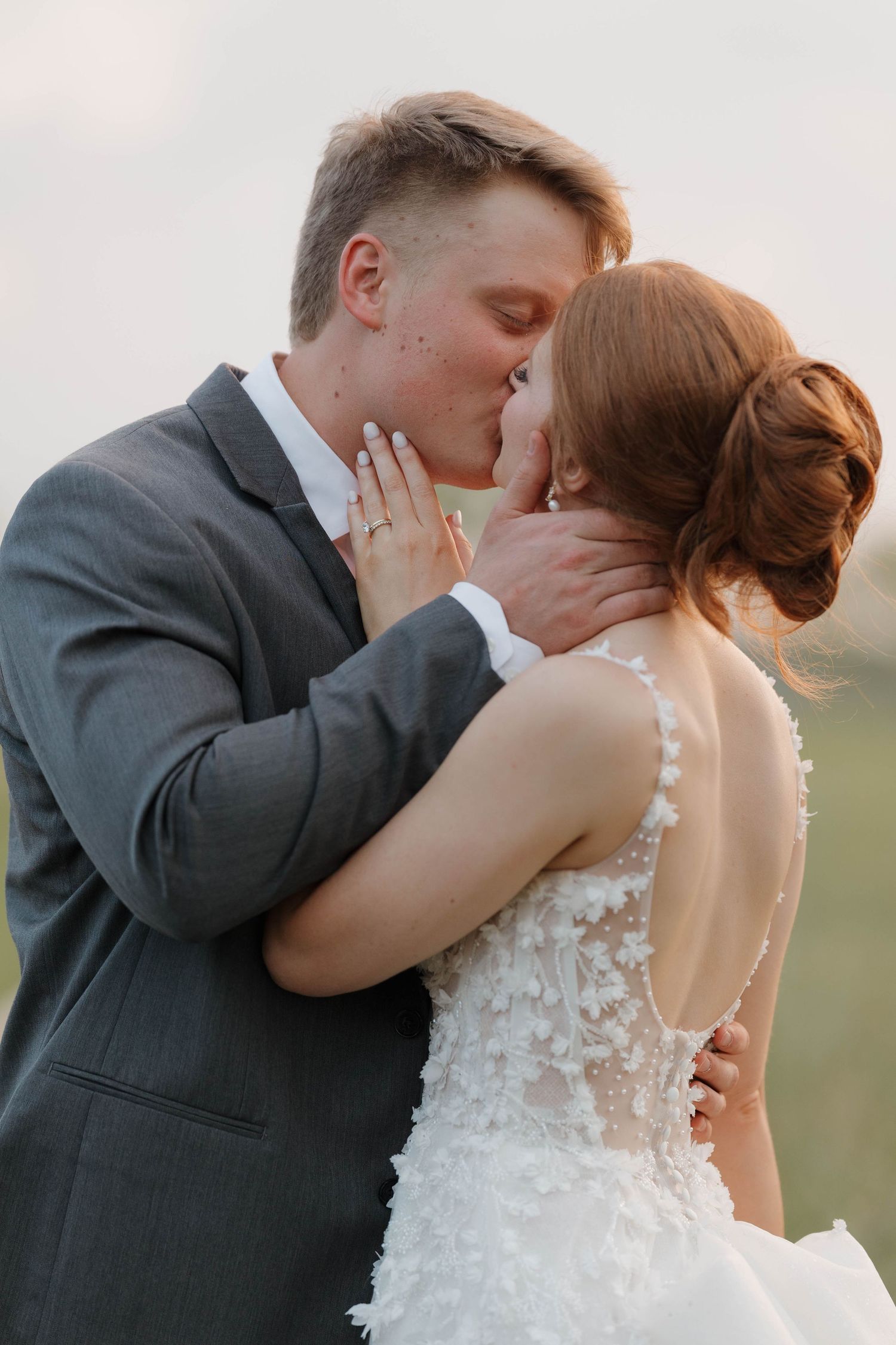 Bride in lace dress and groom in gray suit share romantic kisses in a series of four outdoor wedding photos.