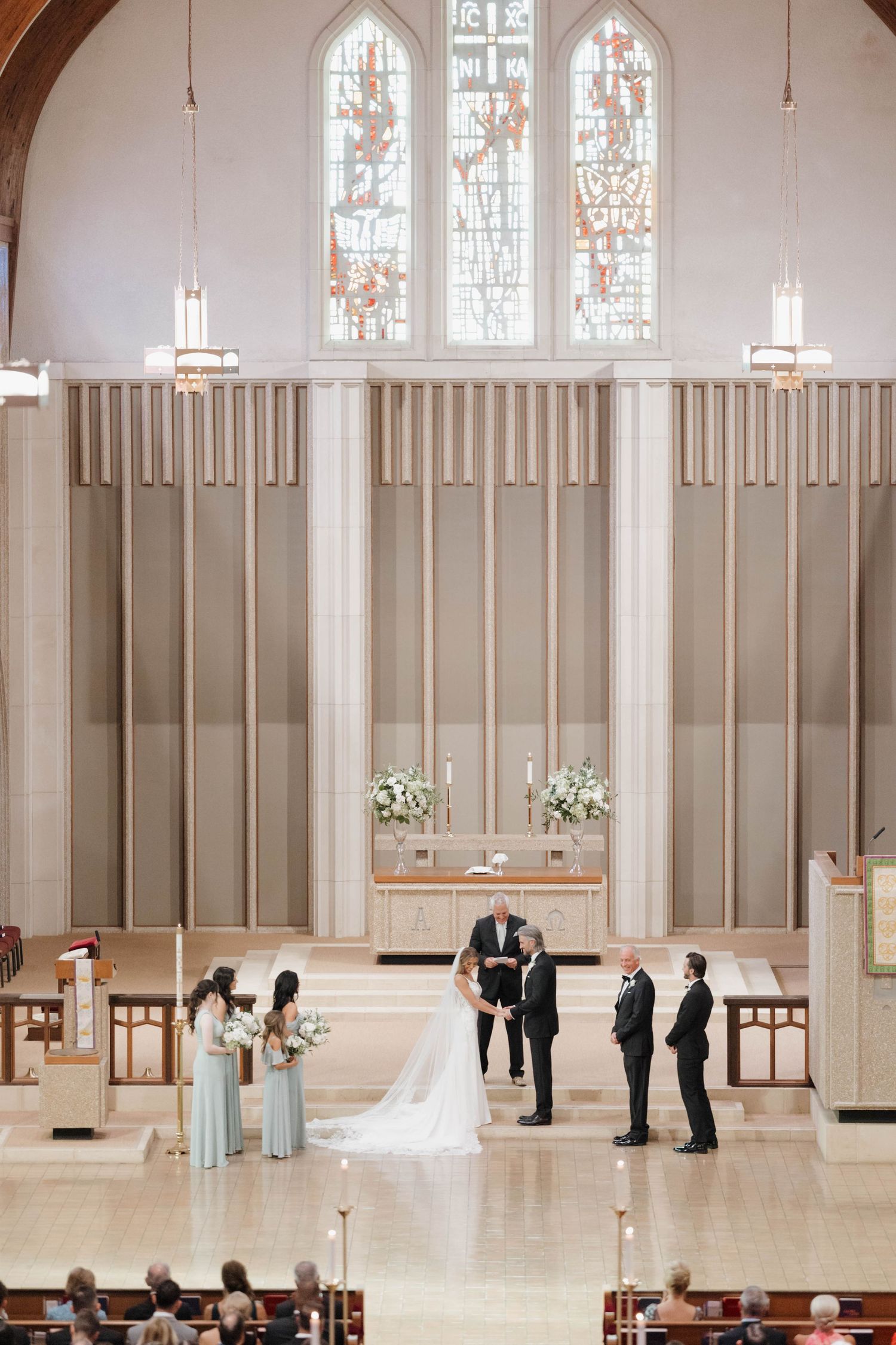 Modern church wedding ceremony with minimalist white interior and stained glass windows.