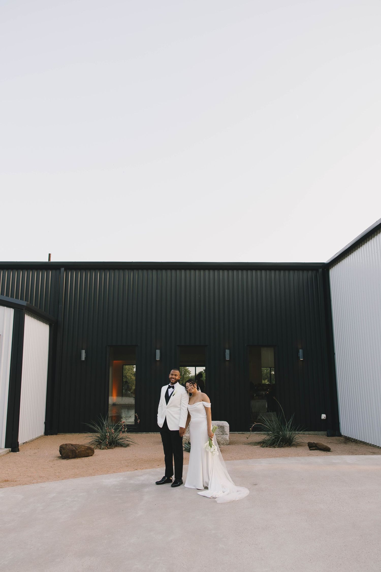 A minimalist outdoor wedding ceremony setup against a modern black and white building exterior.