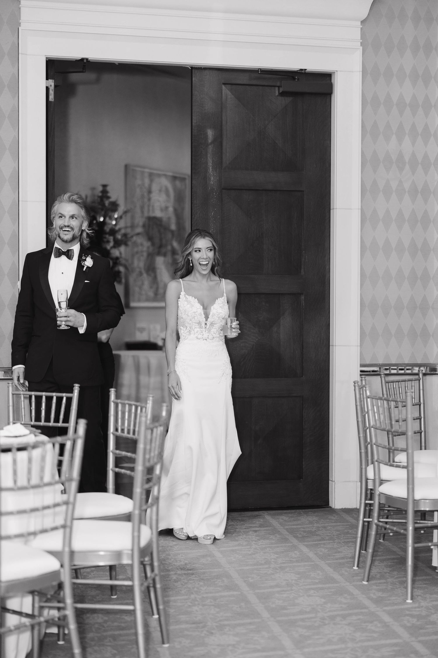 A black and white photo of a couple making their grand entrance into an elegant wedding reception hall.