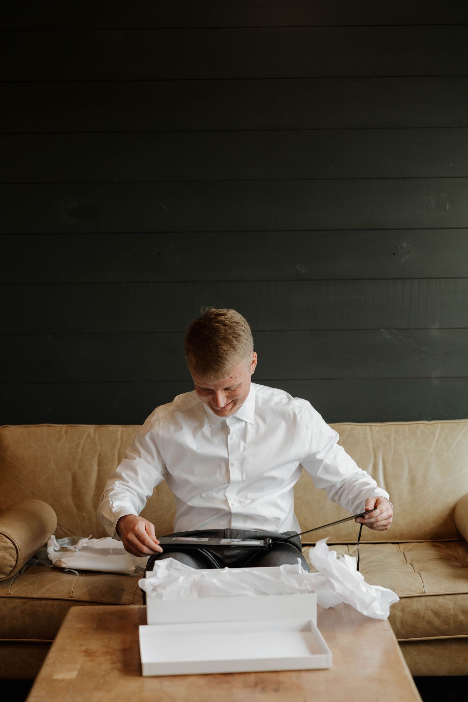 Progressive series shows person in white shirt seated on beige couch slowly opening and unfolding white paper document.