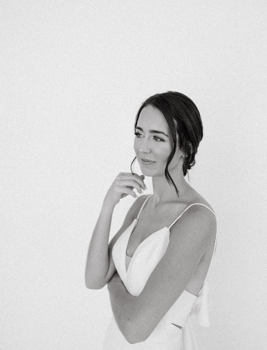 A person in white clothing laughs and covers their mouth in a series of black and white portrait photos.