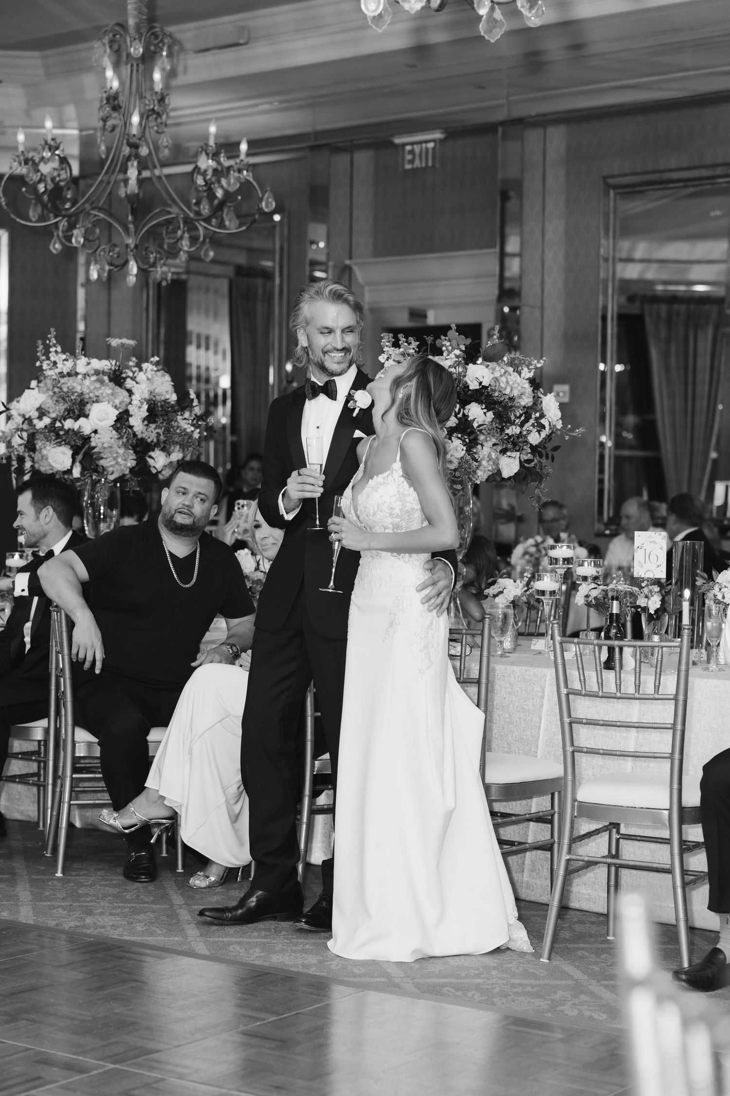 A sequence of black and white photos showing a couple dancing at a formal wedding reception with elegant chandeliers.