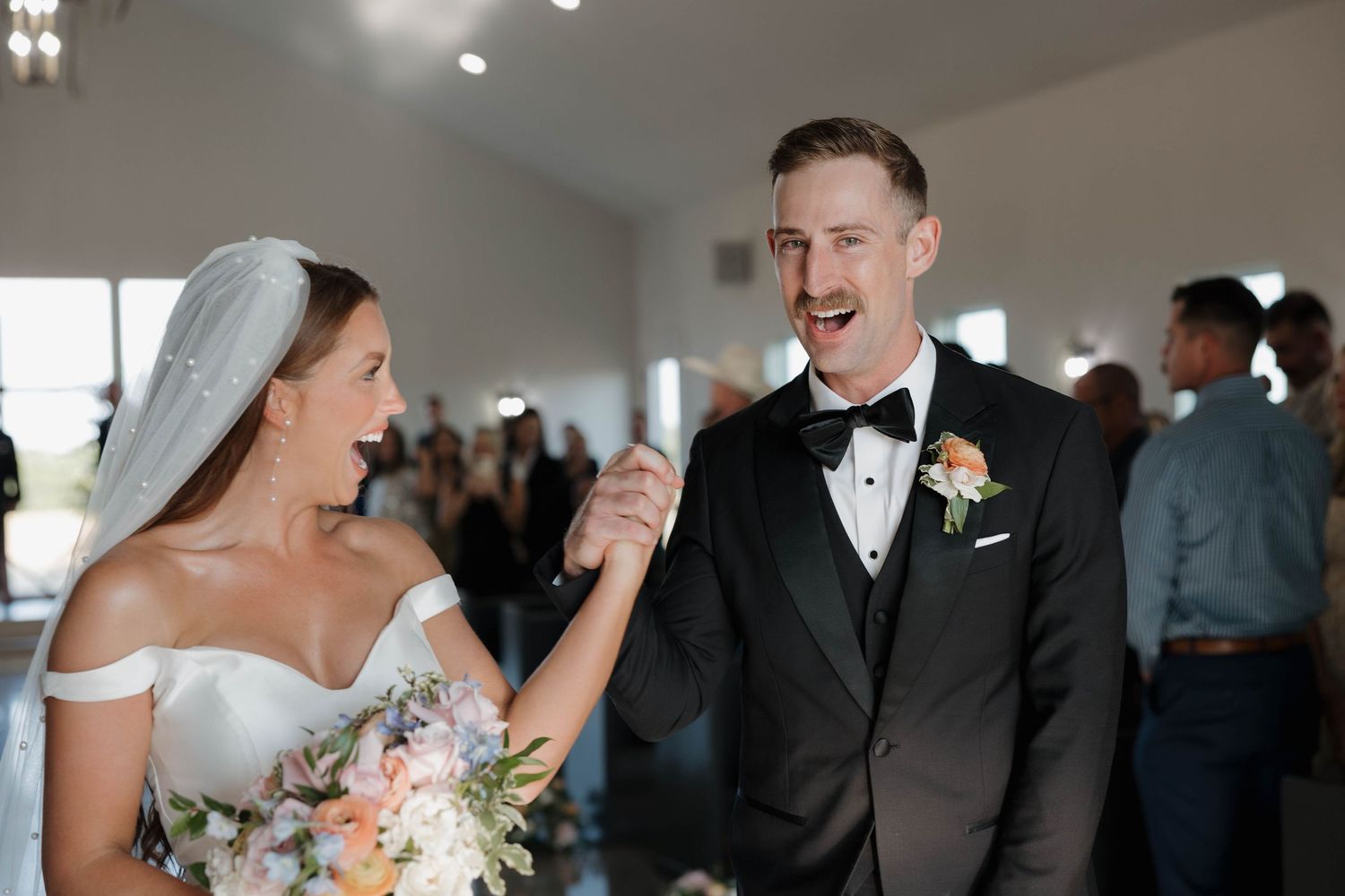 A joyful wedding moment captured in black and white as the newlyweds share a candid laugh together during their celebration.