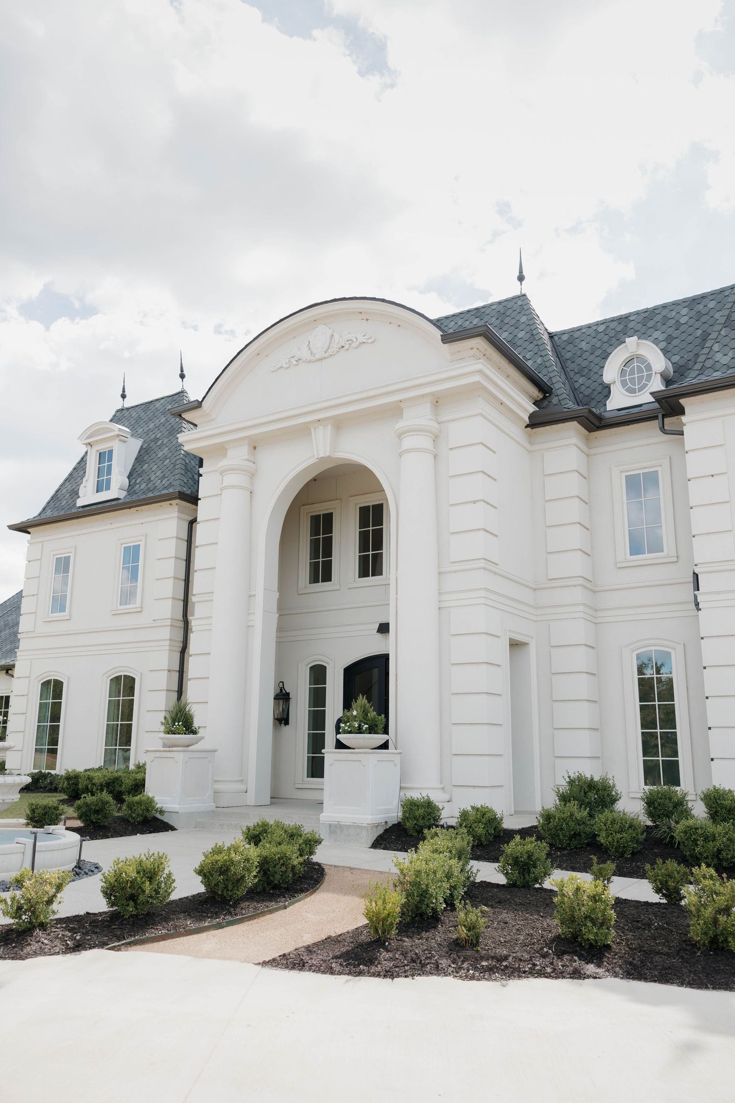 Elegant white mansion with grand entrance and manicured landscaping.