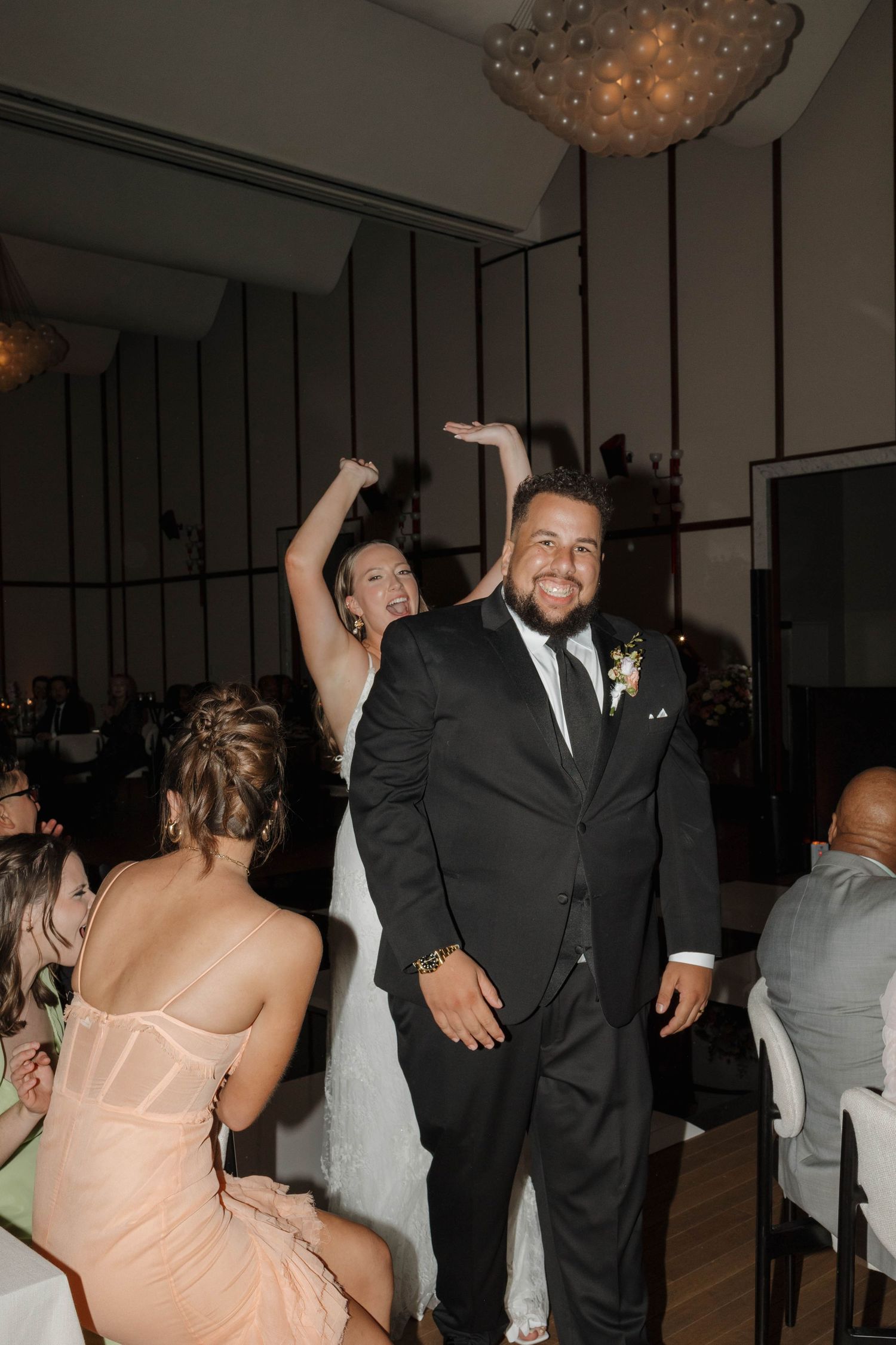 Sequence of candid moments from a wedding reception showing guests dancing and celebrating in an elegant venue with chandeliers.