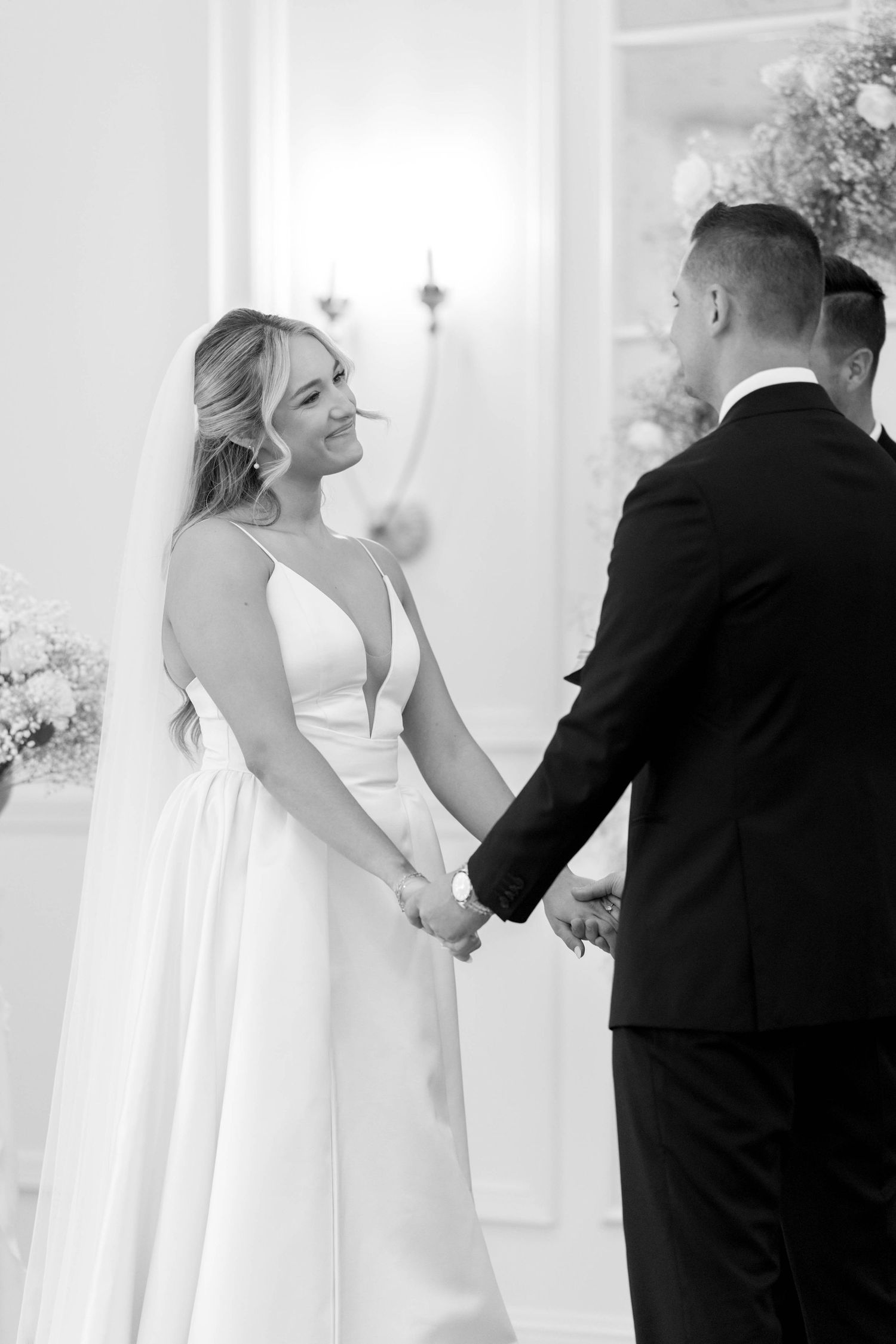A couple shares a joyful moment during their wedding ceremony in a bright white venue.