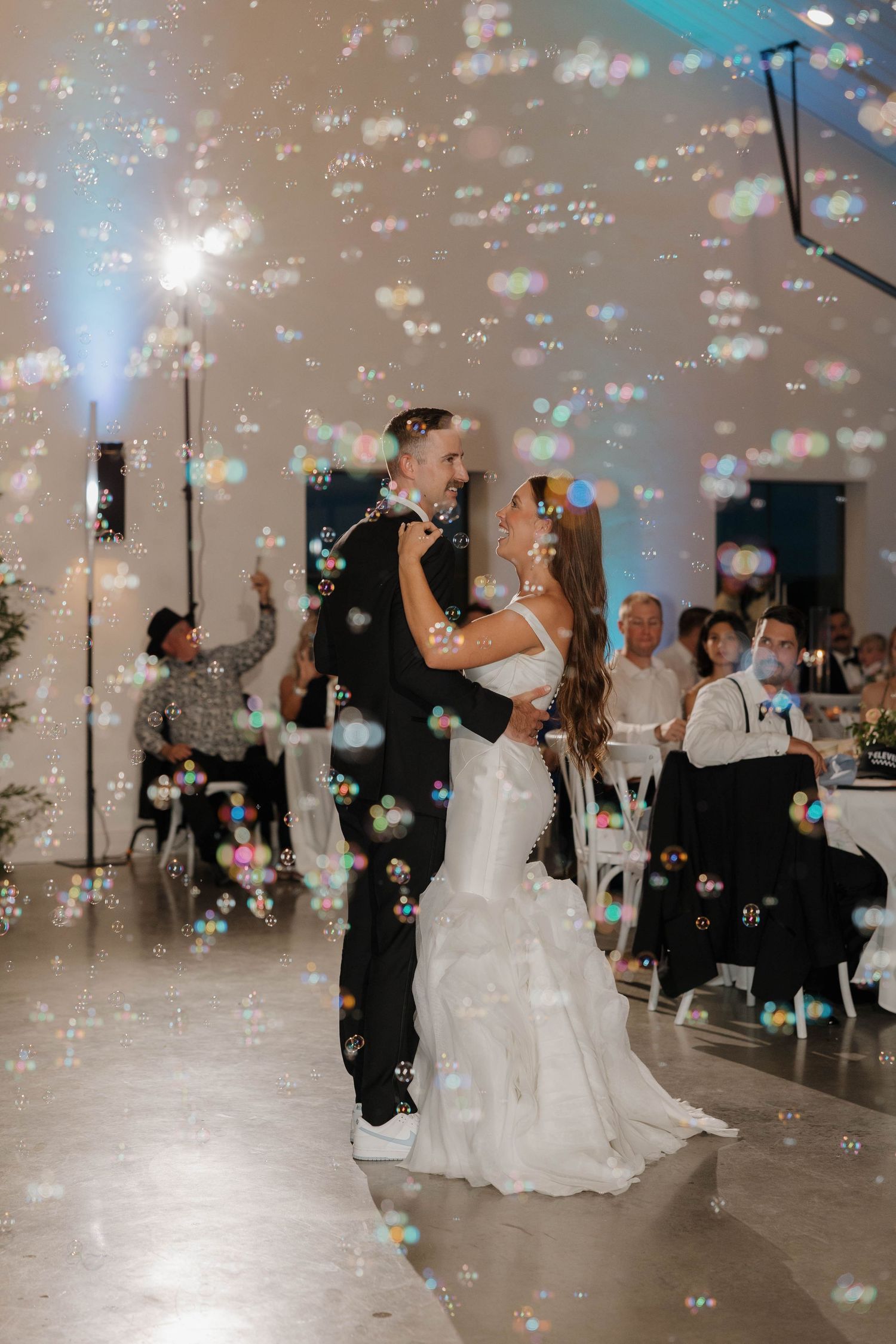 A romantic first dance at a wedding reception with bubbles floating through the air creating a magical atmosphere.