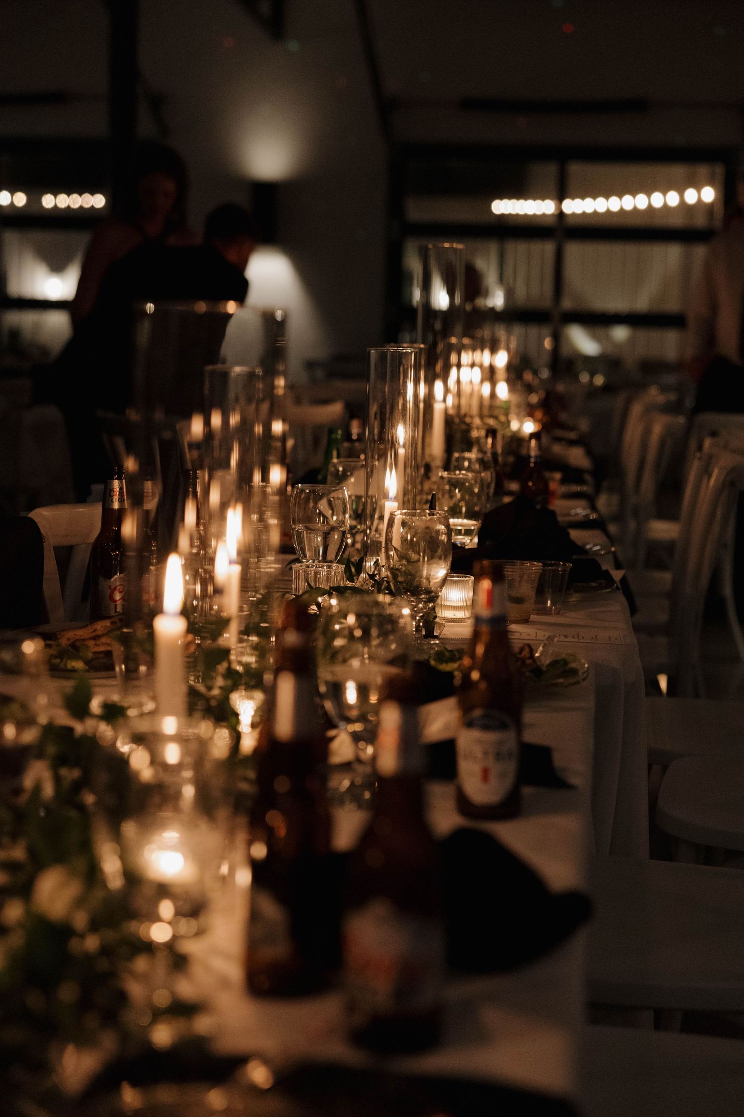 An elegant candlelit table setting with glassware and floral arrangements for a romantic dinner party in warm lighting.
