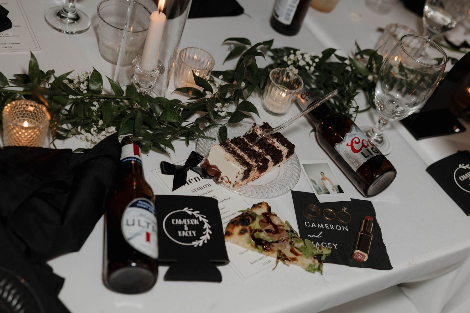 Wedding reception dinner table decorated with glassware, candles and place settings in elegant style.