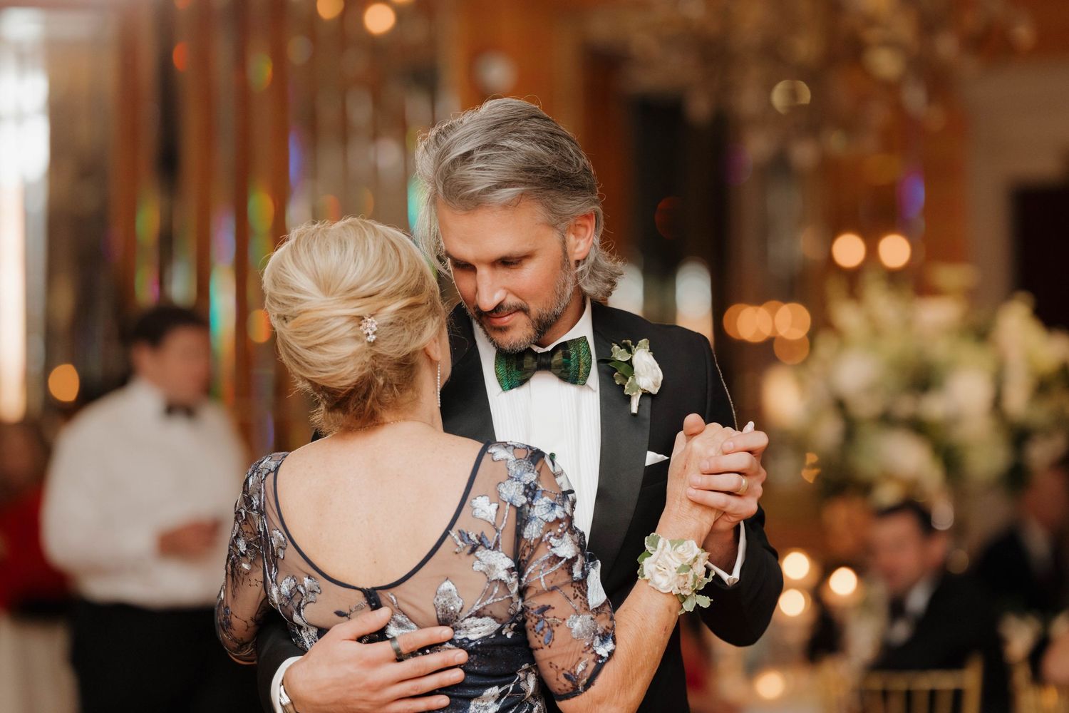 Couple sharing an intimate dance moment at an elegant wedding reception with golden lighting.