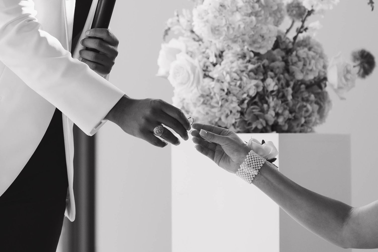 A black and white photo collage of wedding details showing hands, flowers, and elegant table settings.