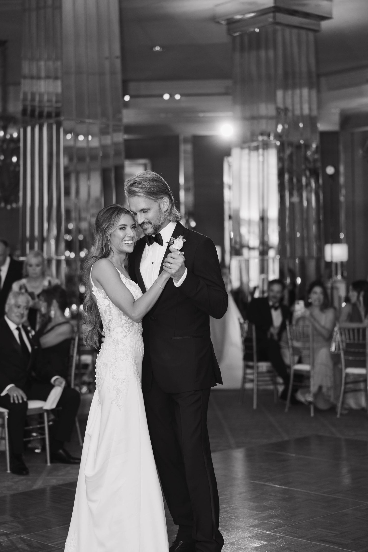 A couple shares an elegant first dance at their wedding reception in a dimly lit ballroom.