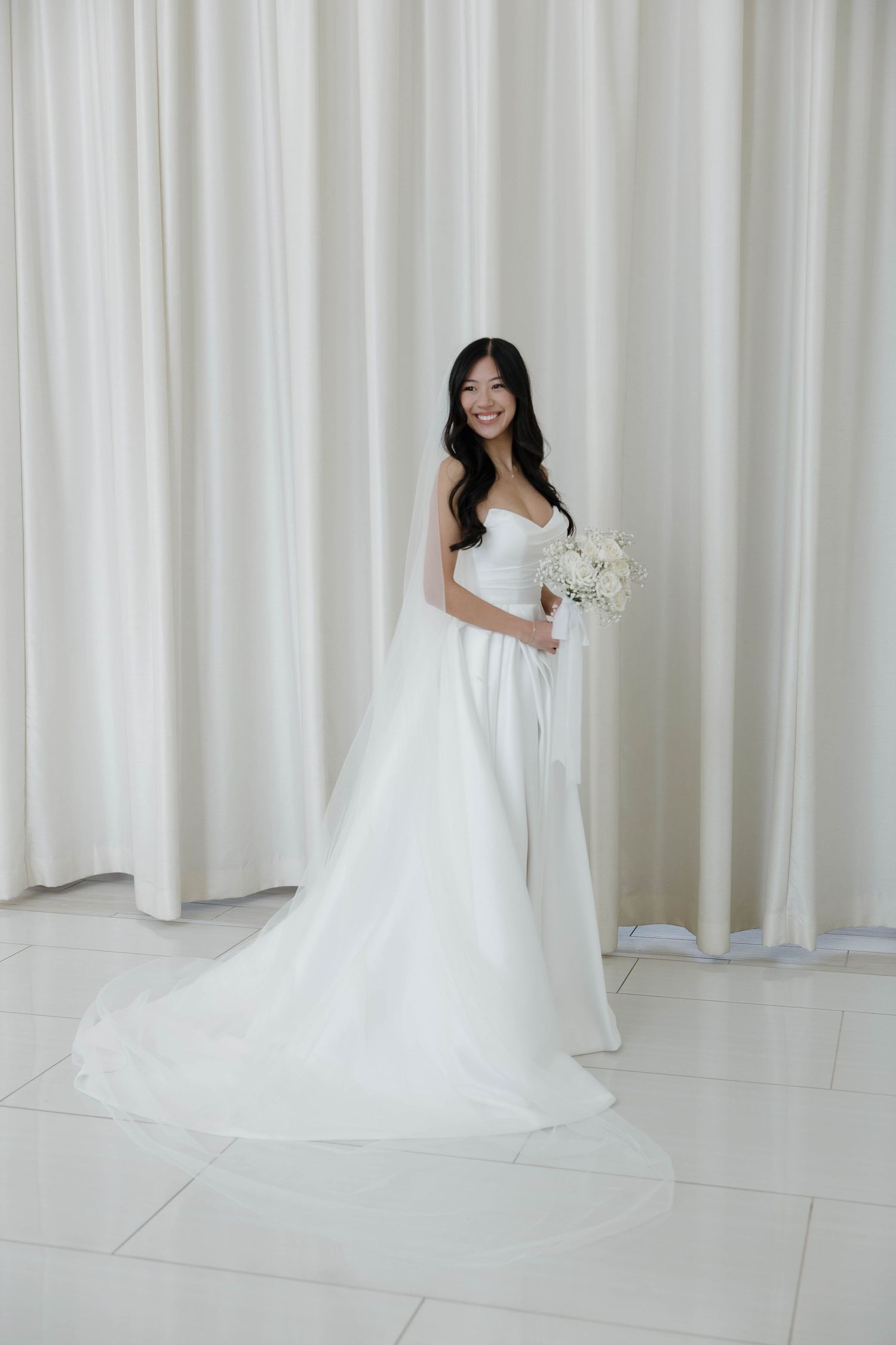 A series of bridal portraits showing a white wedding gown with a flowing train against a light curtain backdrop.