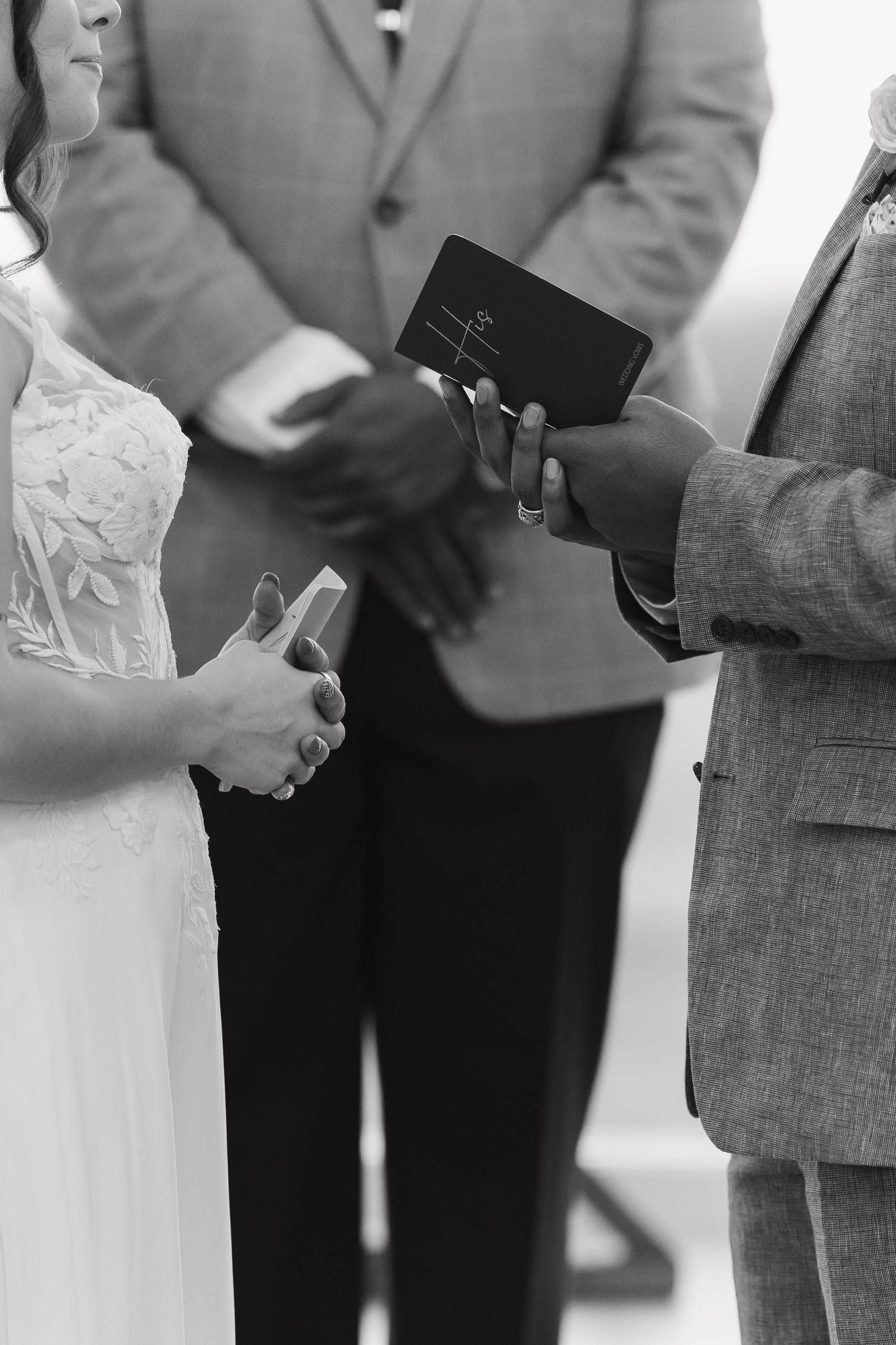 Close-up view of hands holding glasses during a wedding toast between people wearing formal attire.