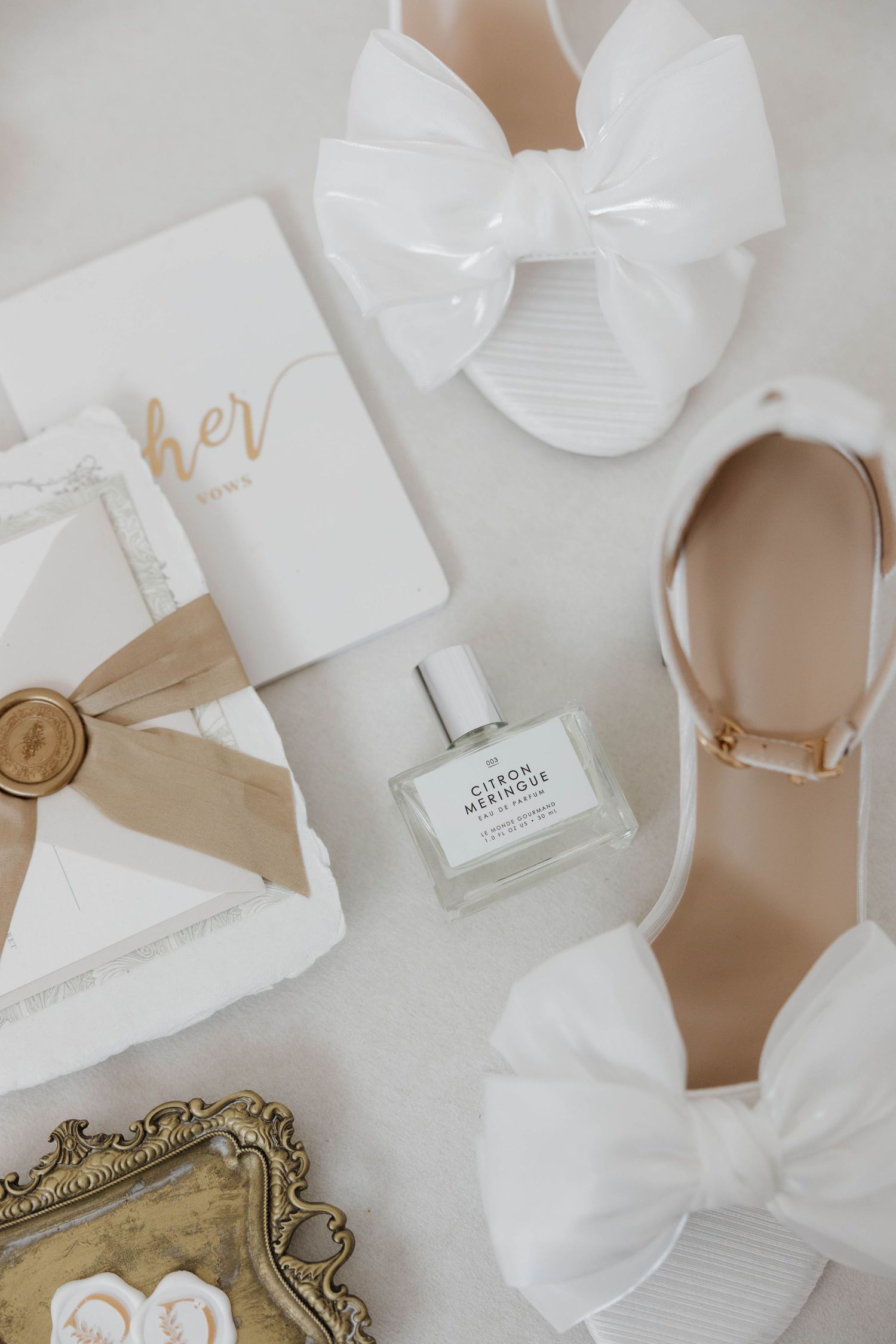 Elegant white wedding stationery and invitations arranged with gold accents and ribbons on a neutral background.