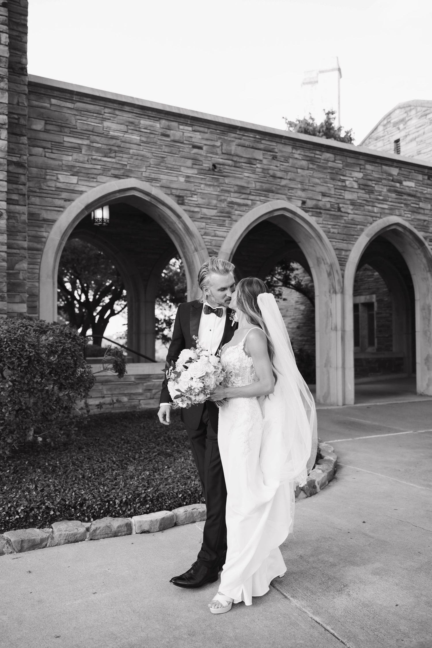 A series of romantic black and white wedding portraits taken under stone archways at an elegant venue.