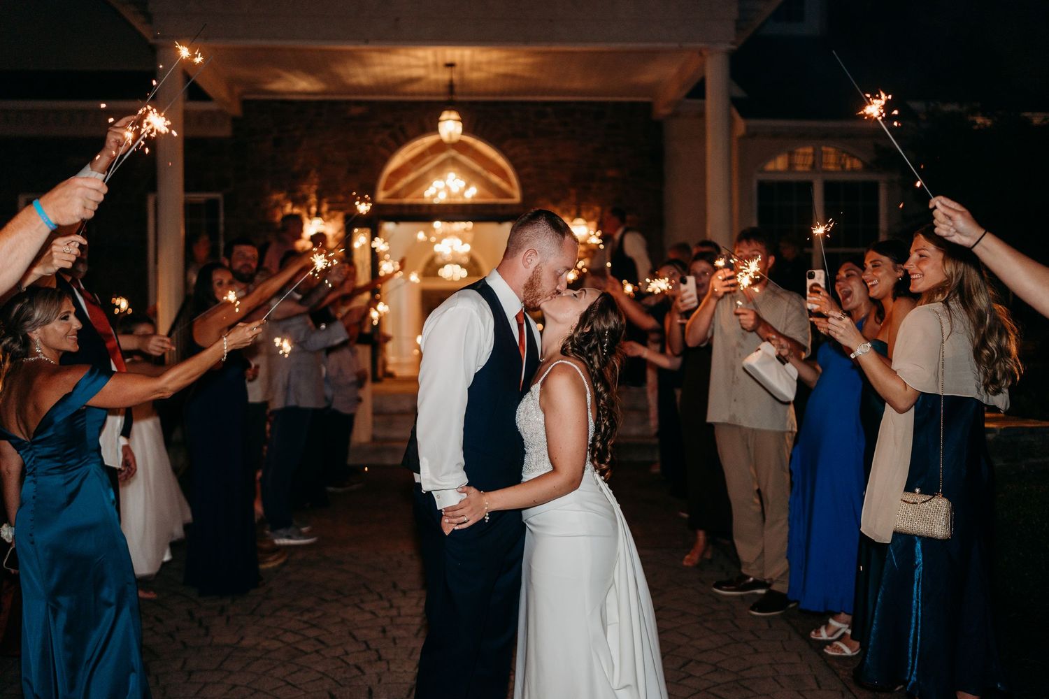 Wedding guests dancing together on a dimly lit dance floor during an evening reception celebration.