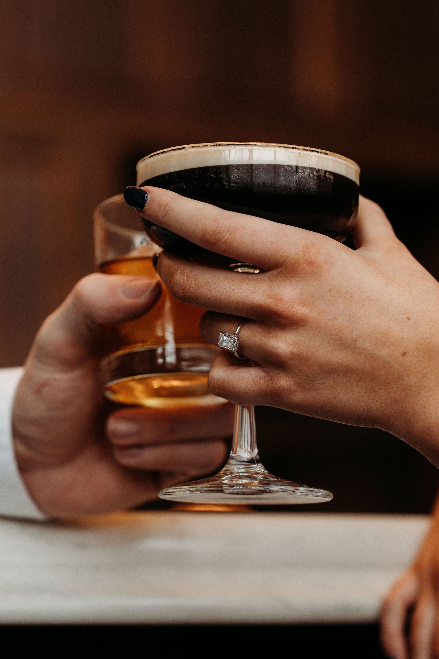 Close-up view of hands holding and adjusting a delicate teacup on a white surface in dim lighting.