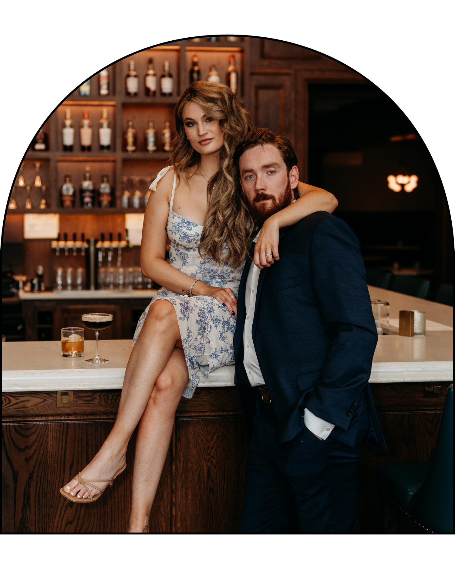 Couple in formal attire sharing intimate moments at a bar counter with warm lighting and bottles in background.