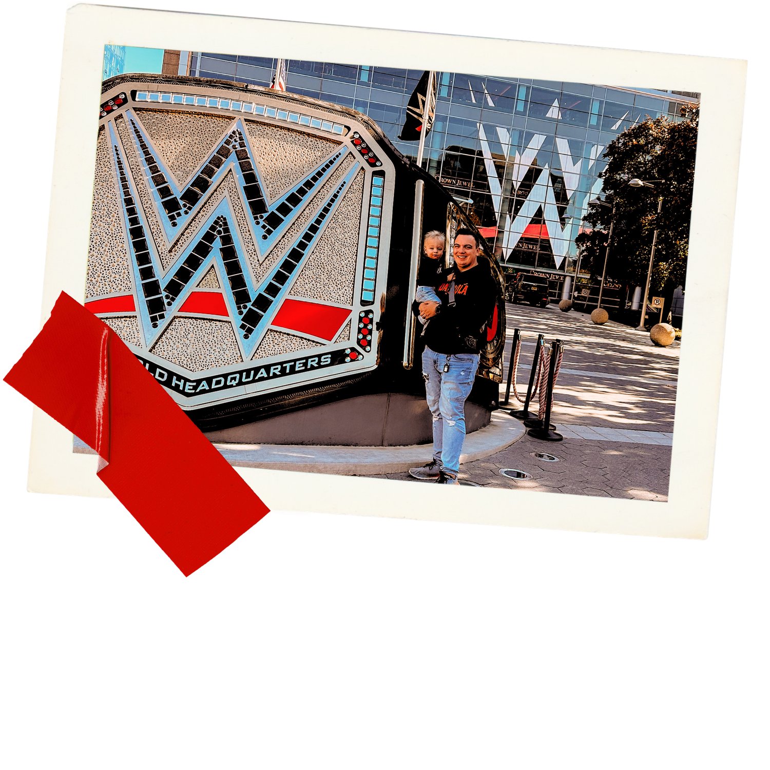 Person poses beside large WWE championship belt logo display outside building.