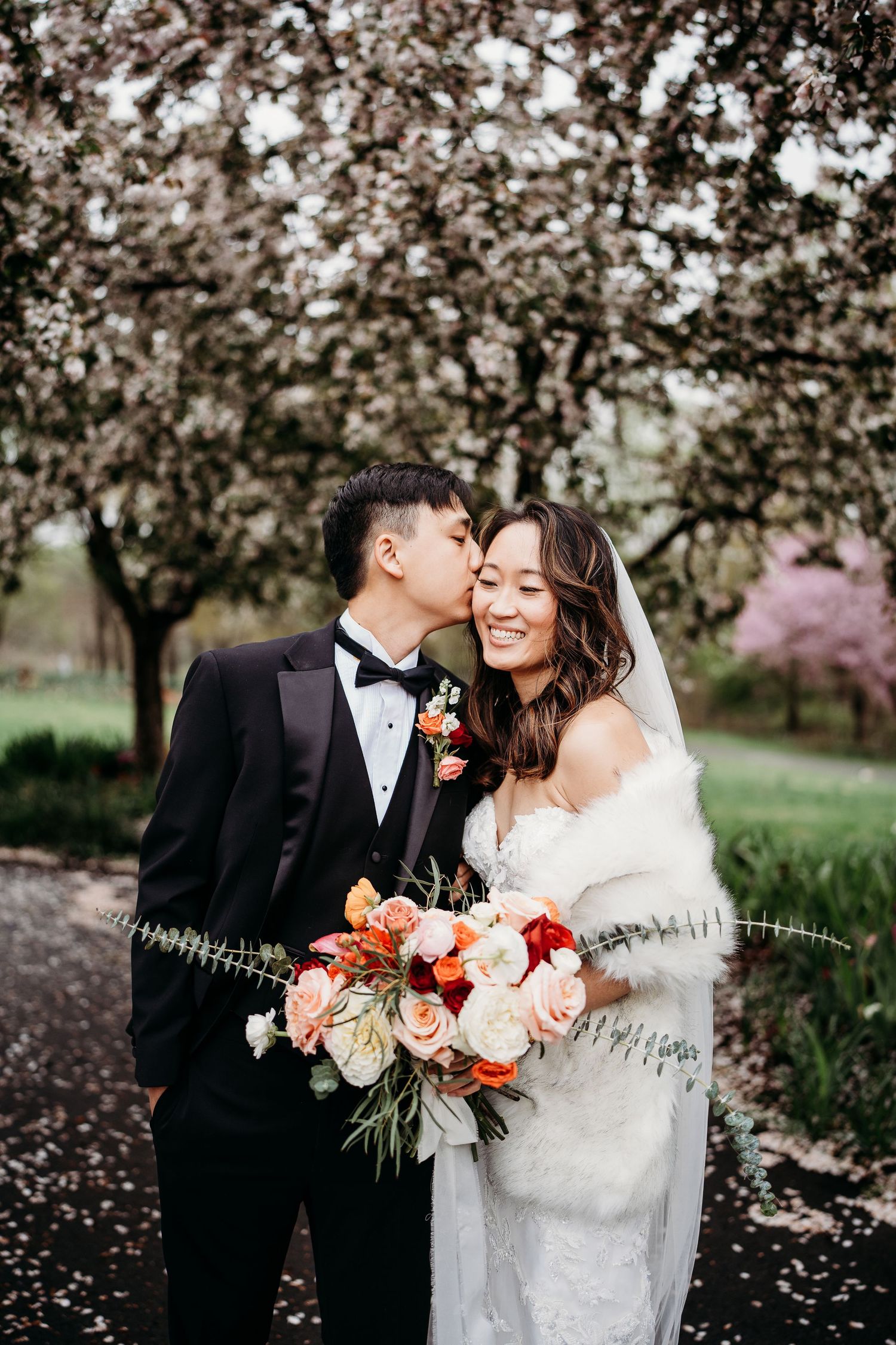 A romantic wedding photo series showing tender moments between newlyweds under blooming cherry blossom trees.