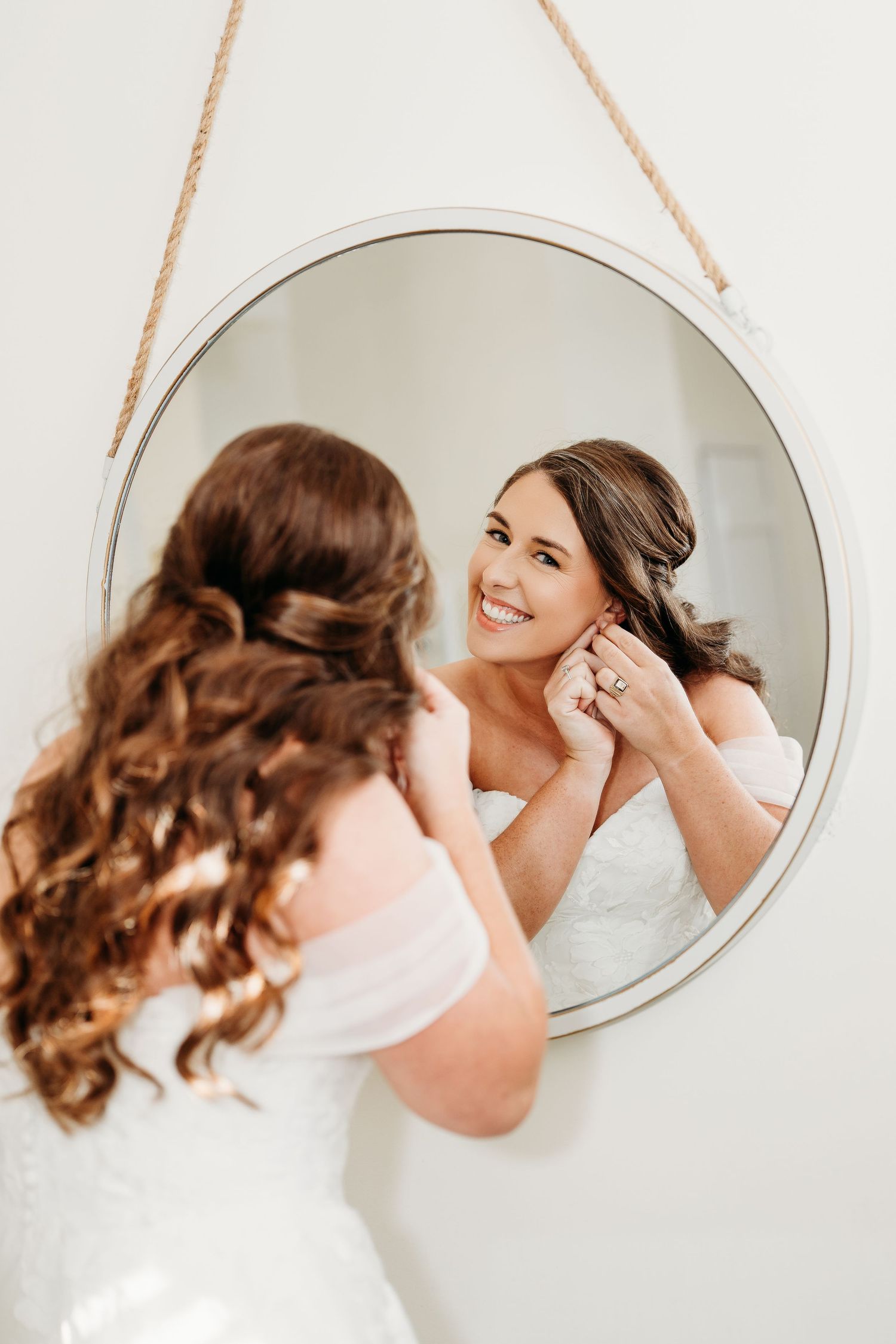 Four sequential mirror reflections show someone brushing and styling curly brown hair against a white background.