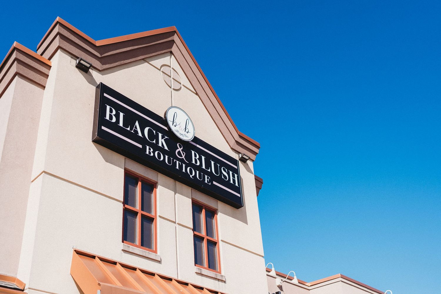 Low angle view of Black & Main restaurant sign on white building facade against blue sky.