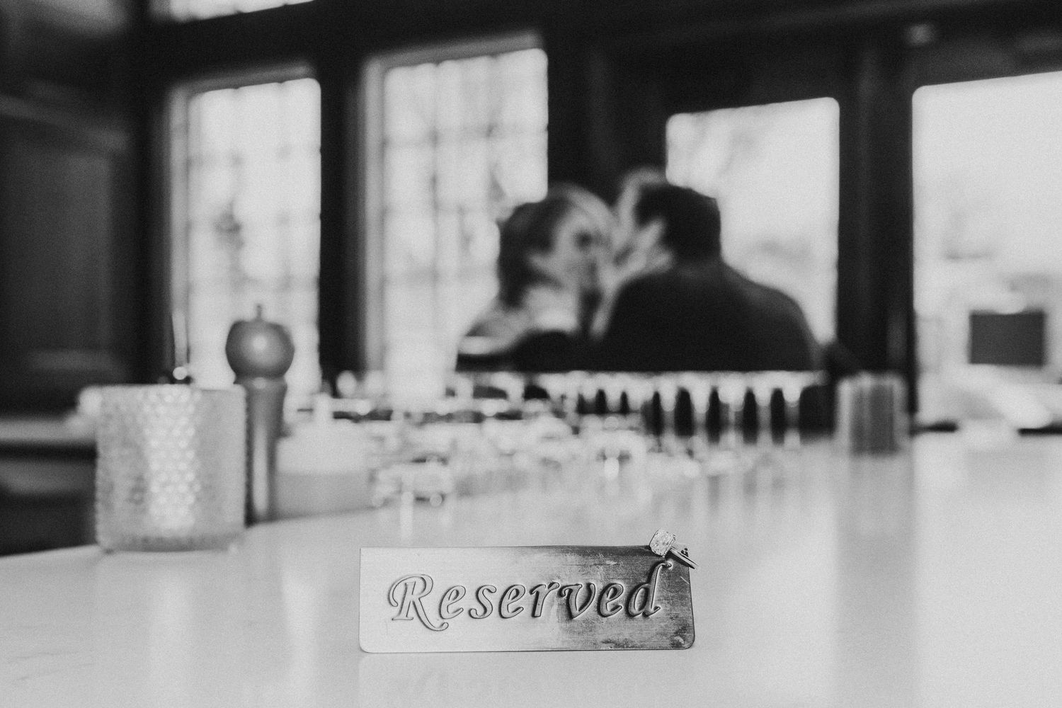 Black and white detail shot of a reserved sign on a bar counter with blurred background.