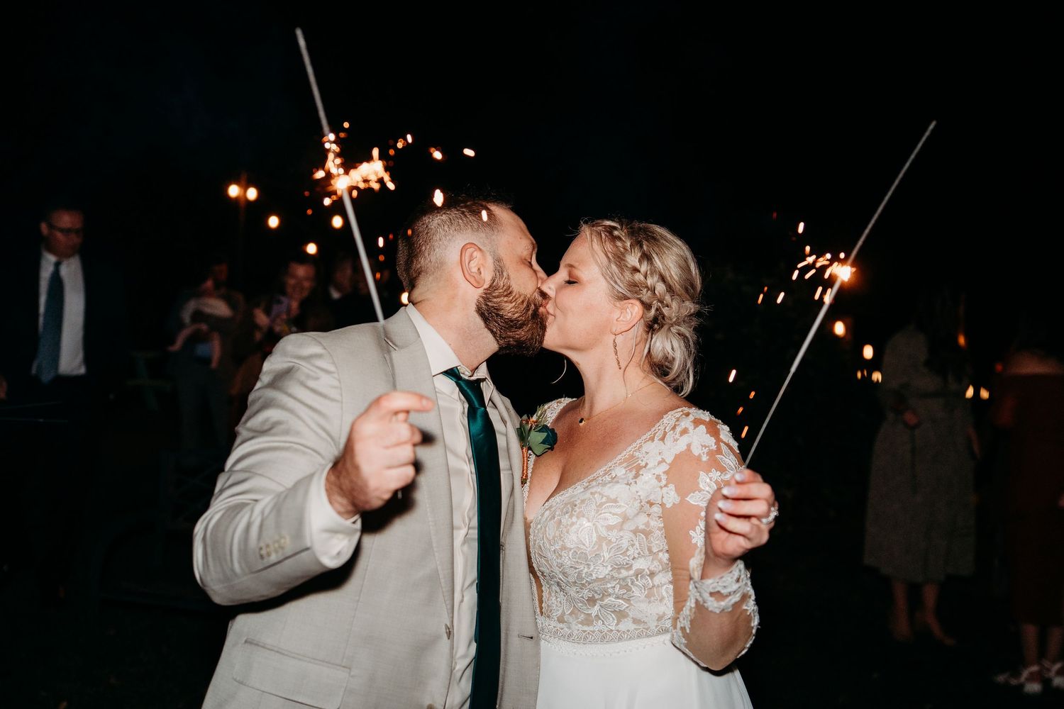 Couple shares a romantic dance with sparklers during an evening wedding reception celebration.