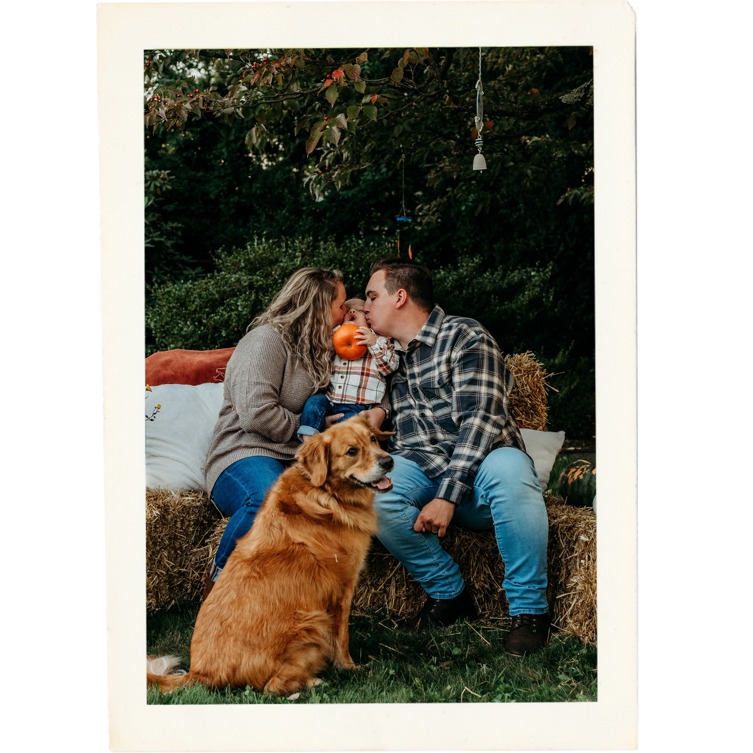 Couple shares intimate moment on hay bale with golden retriever during autumn engagement shoot.