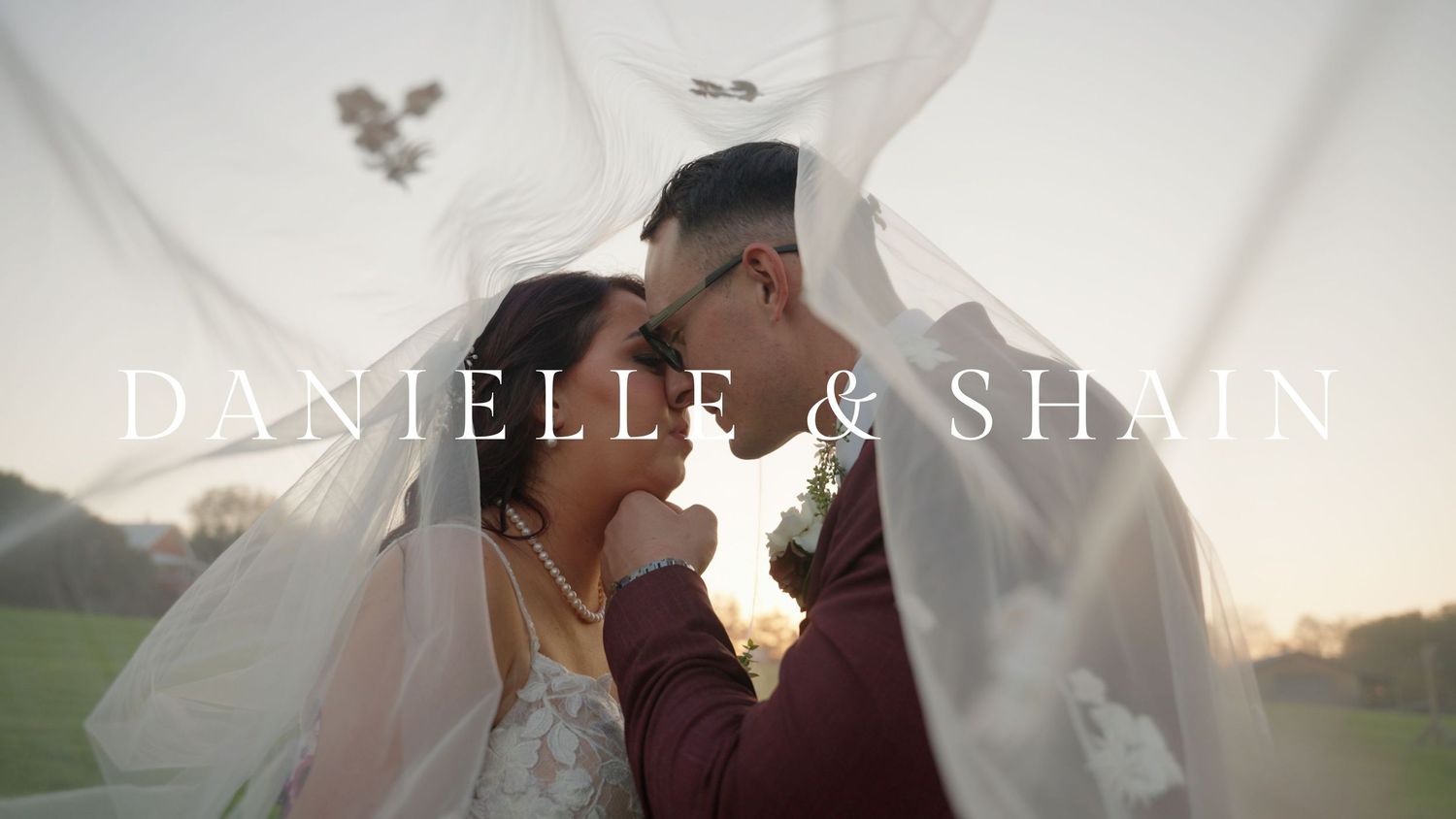 A couple embraces in a romantic outdoor setting at sunset with soft golden lighting and natural scenery.