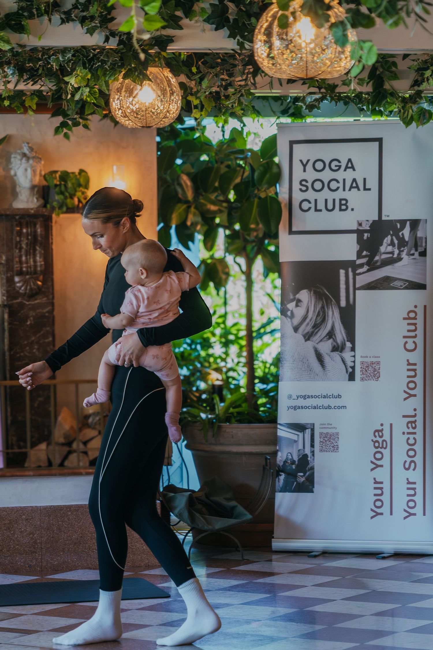 A yoga studio interior with green plants and decorative elements shows a fitness session in progress.