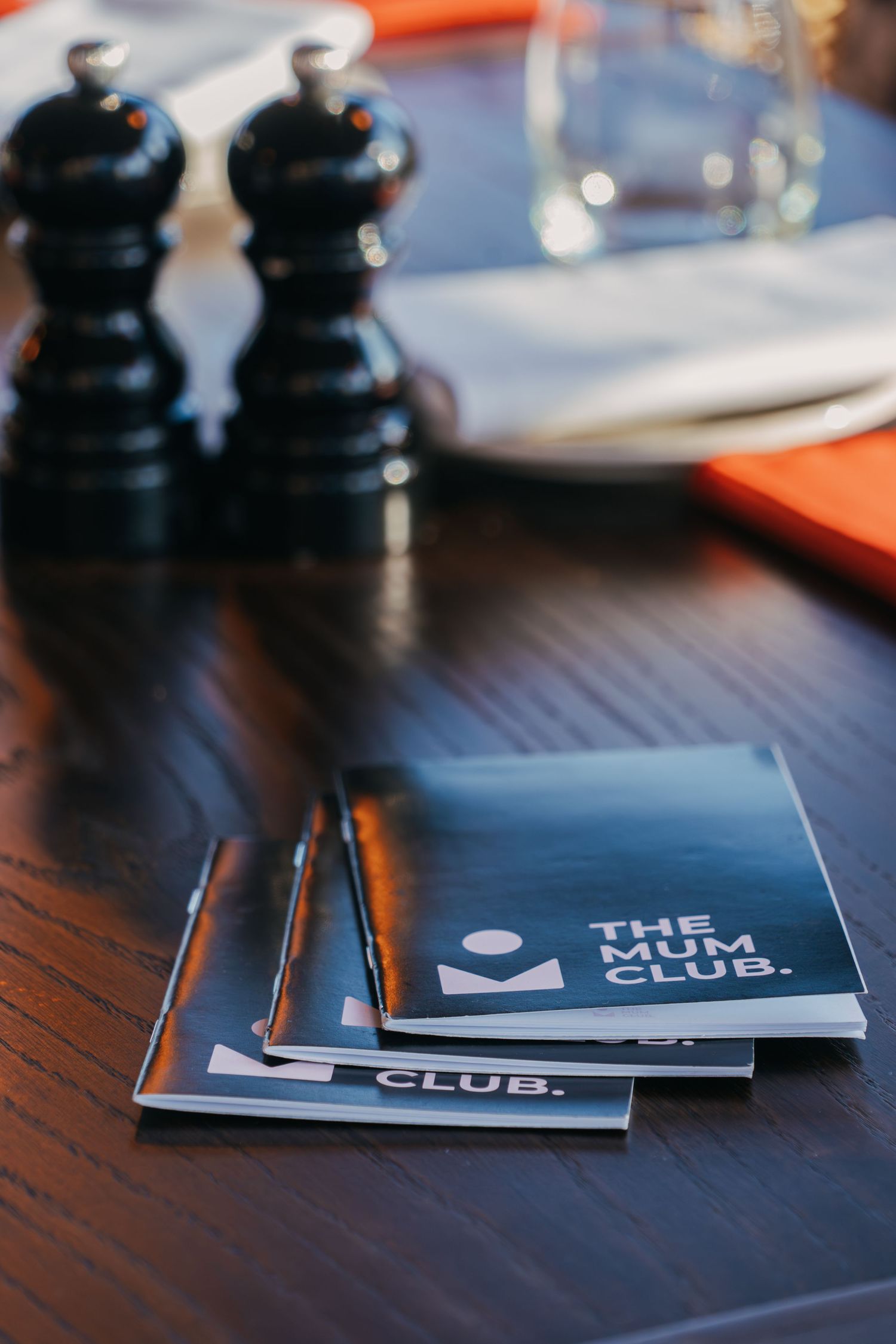 Black salt and pepper shakers next to 'The Gym Club' branded cards on a dark wooden table.