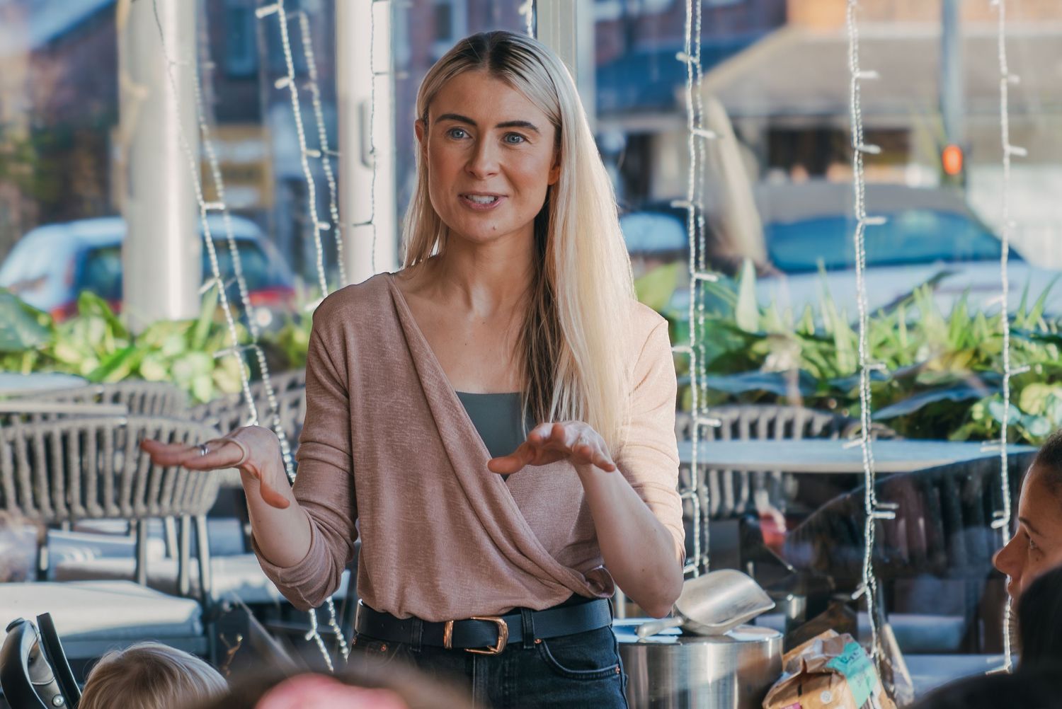 A person sits at an outdoor cafe table with a laptop and smartphone while working remotely.