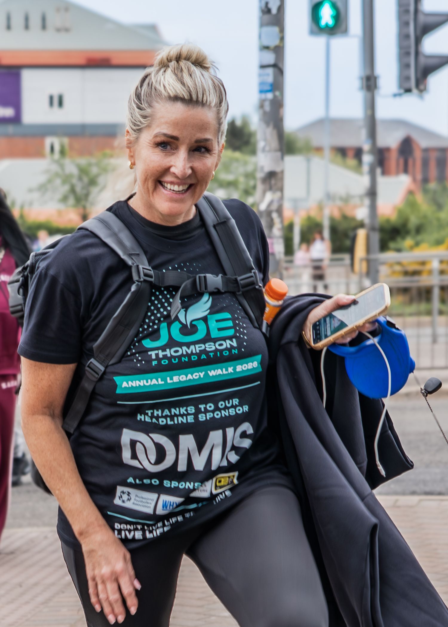 Woman smiling outdoors wearing a Joe Thompson Foundation Annual Legacy Walk 2023 charity event t-shirt.