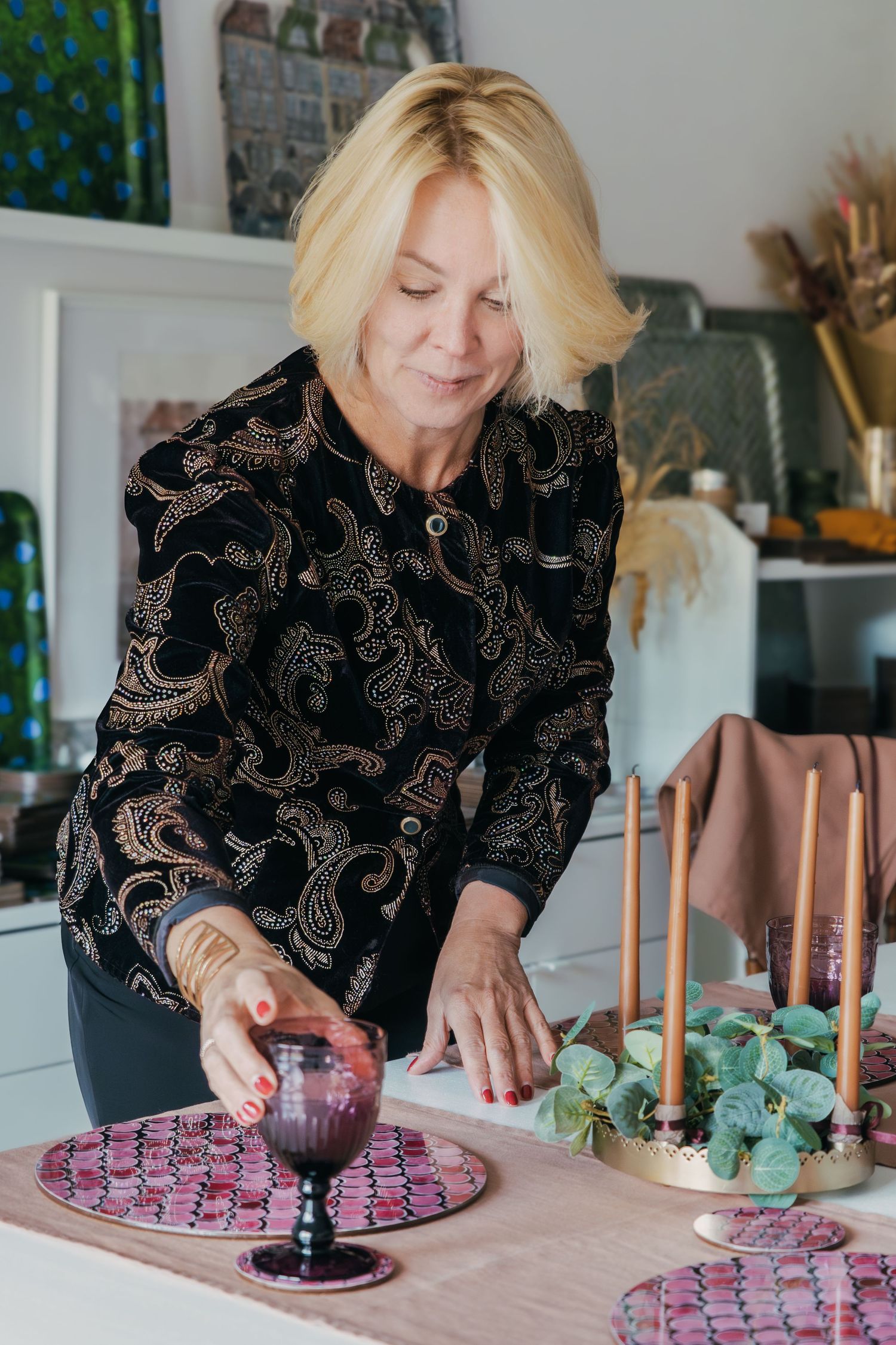 A series of photos showing hands arranging purple candles and decorative elements on a pink tablecloth for a table setting.
