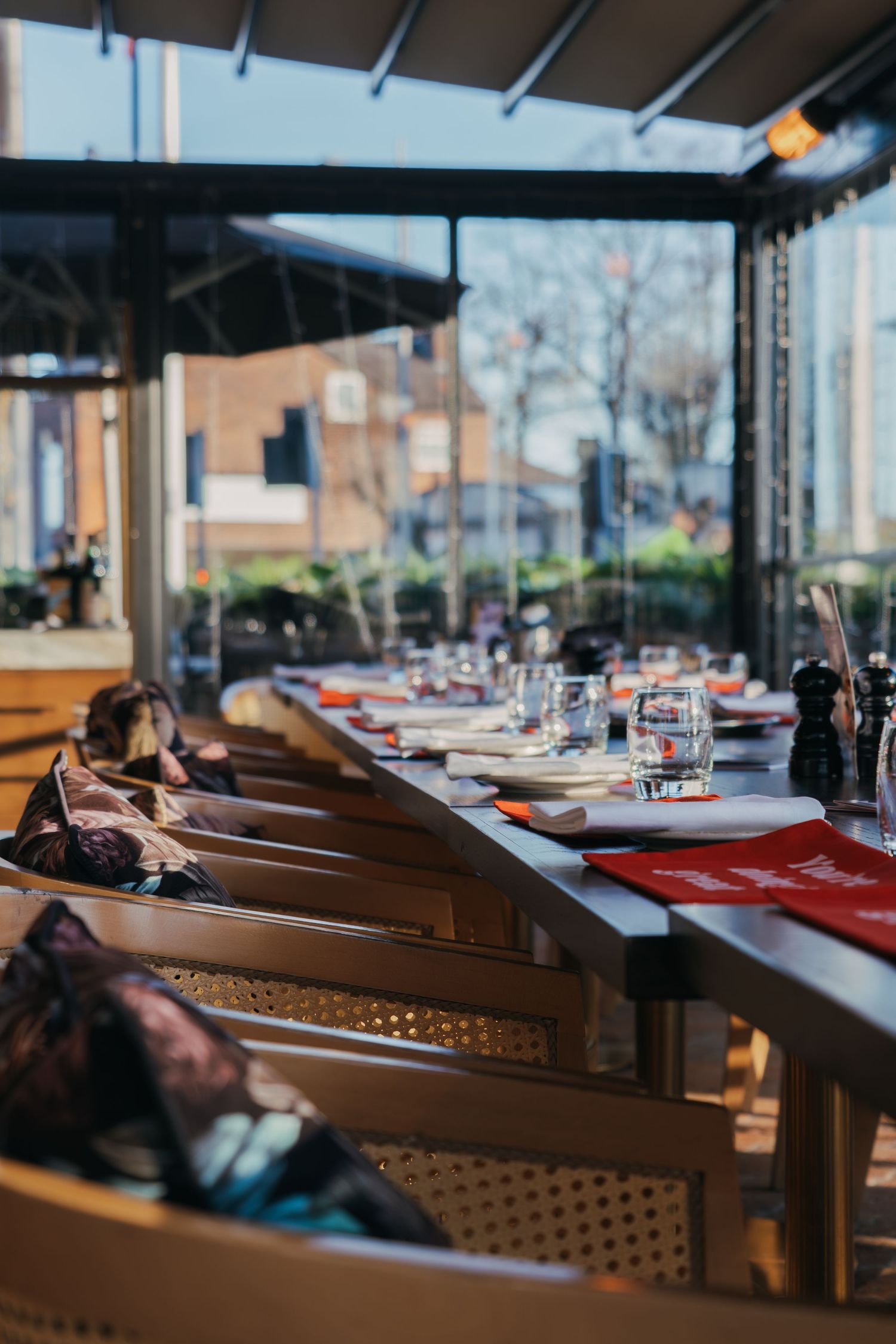 Restaurant interior with wooden tables set for dining, featuring natural lighting and modern decor.