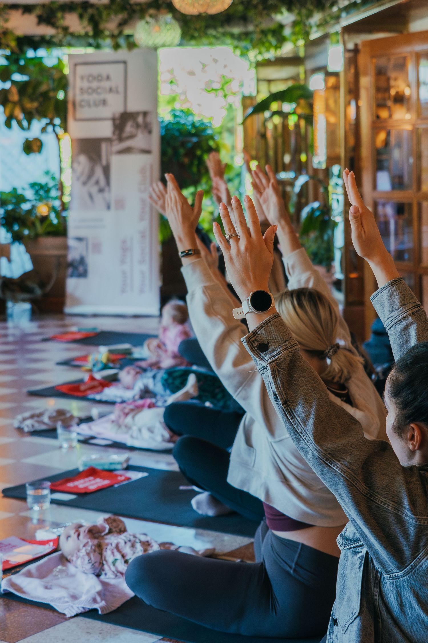 Group of participants with raised hands participating in an indoor workshop session at a community gathering place.