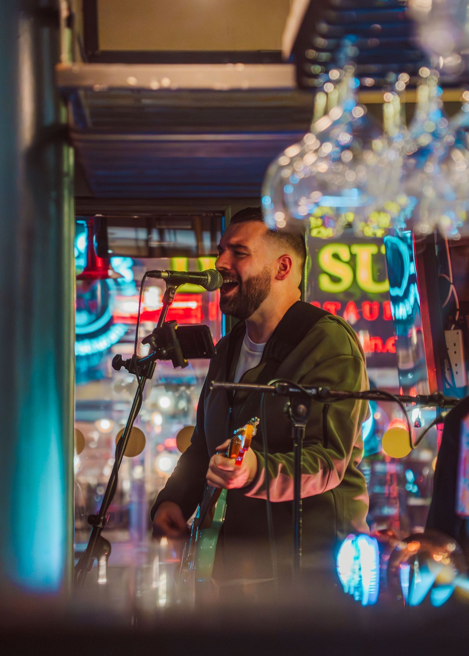 A musician performs at a venue with neon lights and bokeh effects in the background creating an atmospheric ambiance.