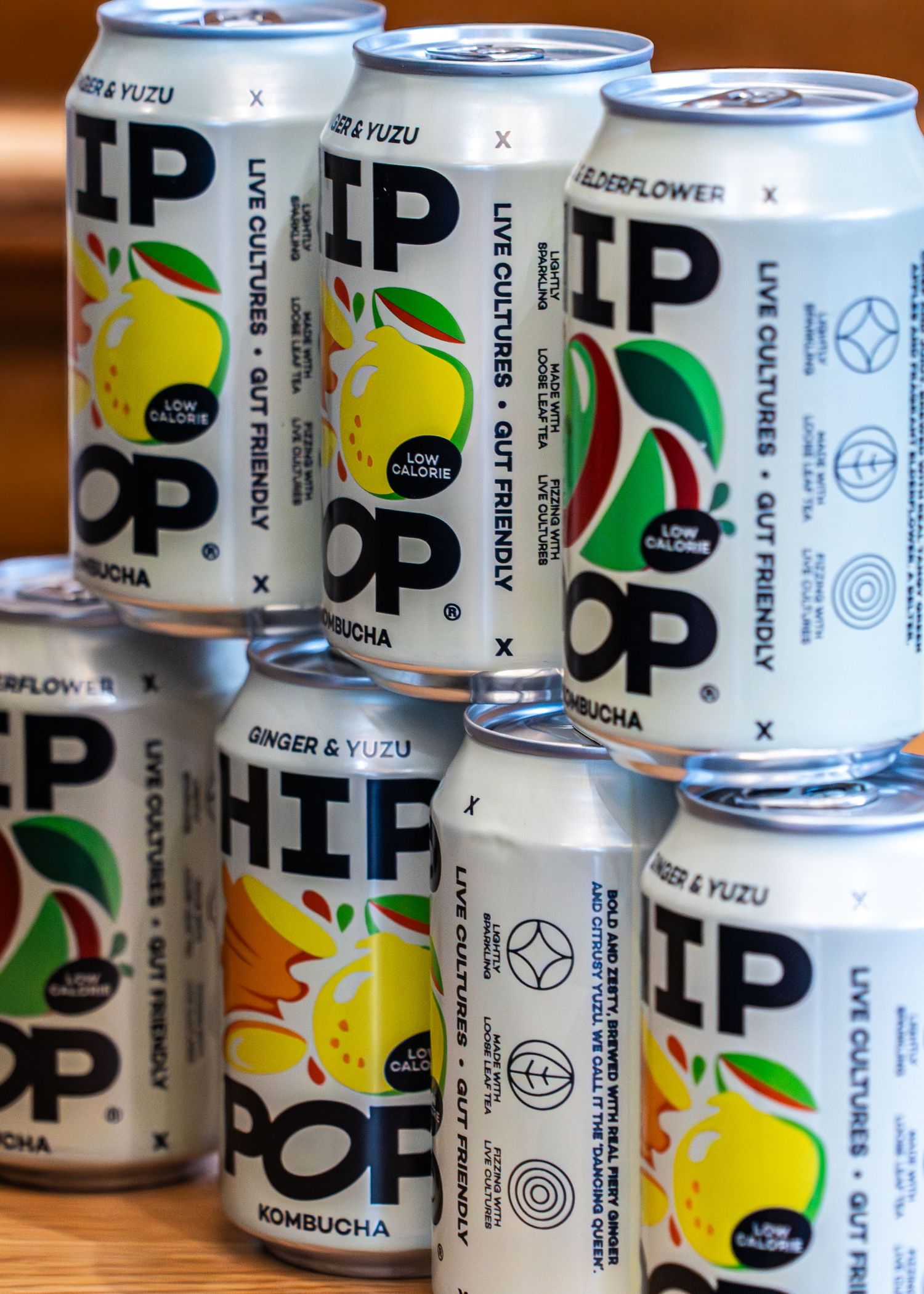 Multiple cans of UP kombucha drinks lined up showing black and white branding with yellow and green accents.