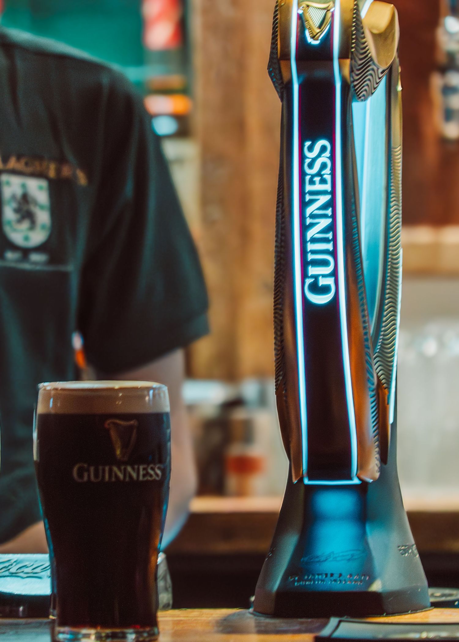 Multiple pints of dark Guinness beer lined up on a bar counter with their distinctive tap handles visible in the background.