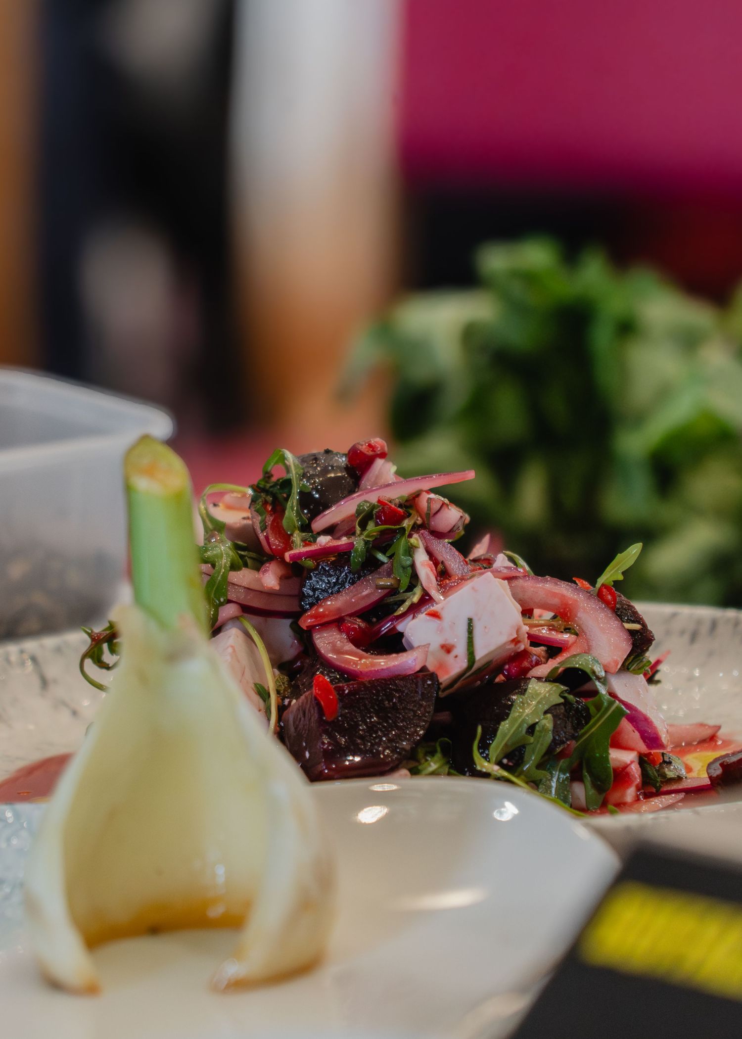 A close-up view of a colorful salad with fresh greens and pink-hued ingredients on a white plate.