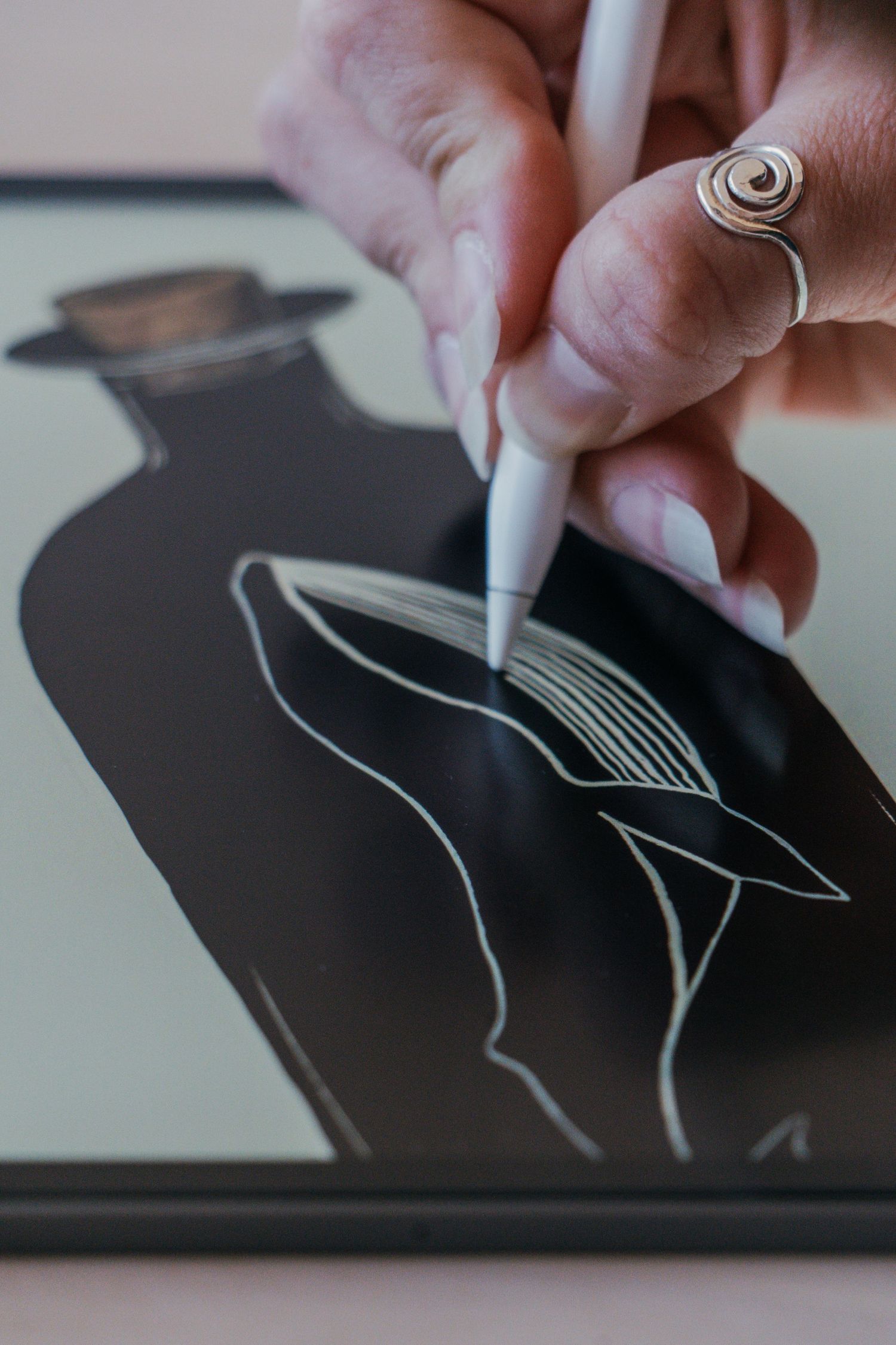 A hand draws white lines on a black surface creating minimalist artwork with a marker or pen.