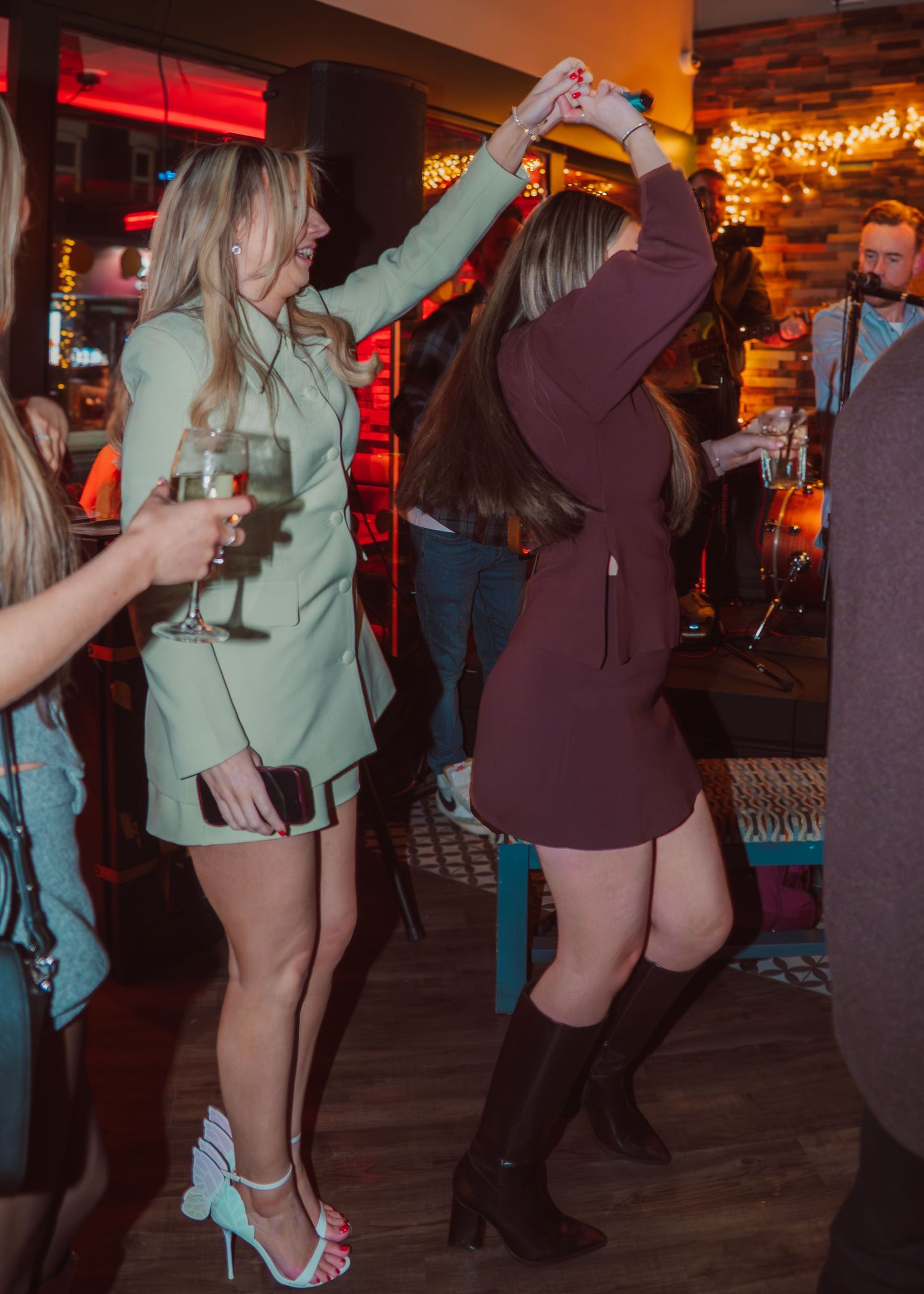 People dancing in a dimly lit bar with neon lights and string lights creating a festive nightlife atmosphere.