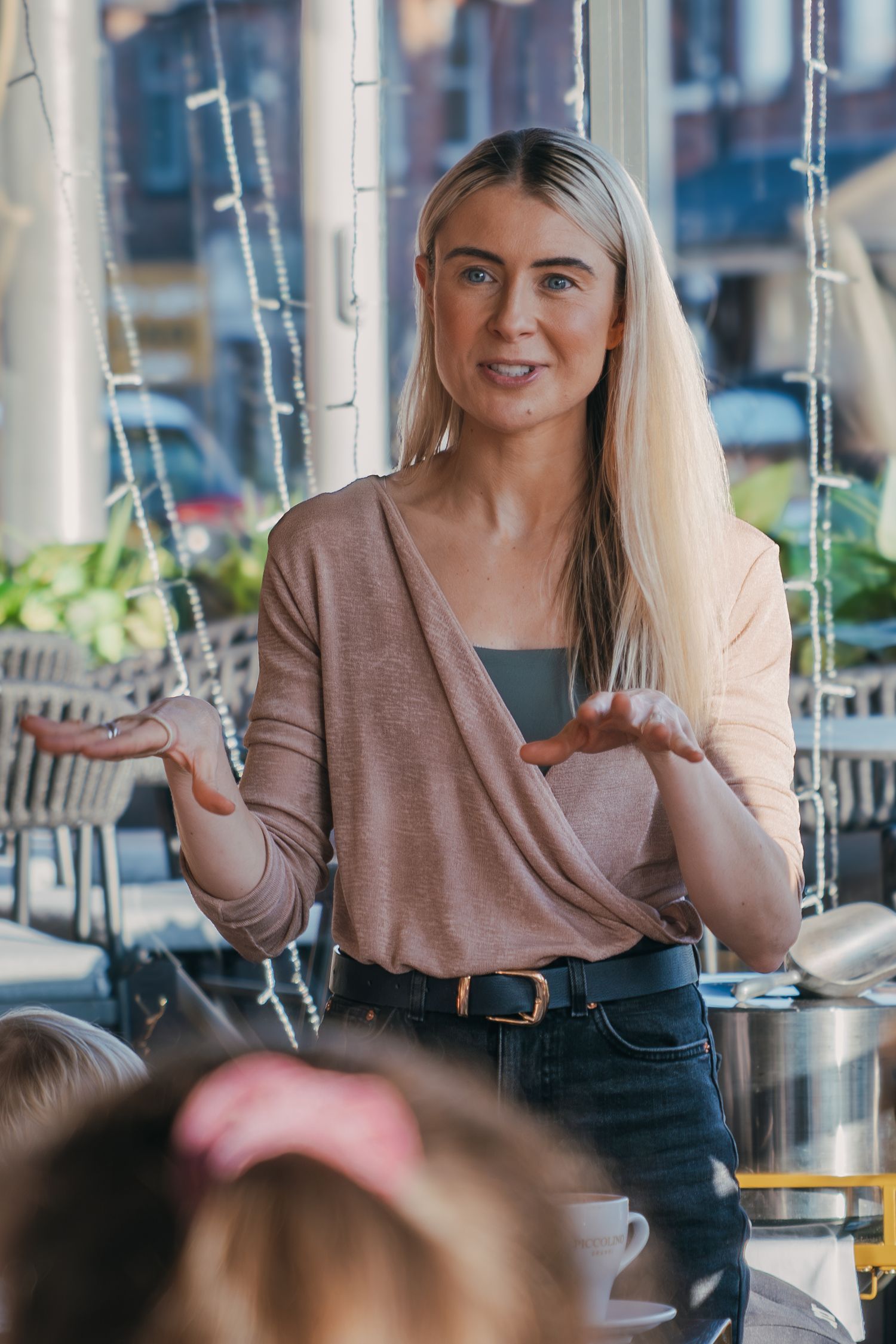 A woman in a beige sweater gestures while speaking in an animated sequence of four connected photos.