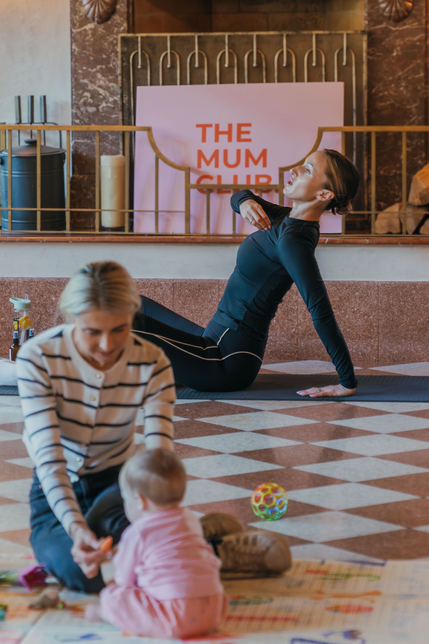 Parent and child play together on a checkered floor with colorful toys and learning materials.
