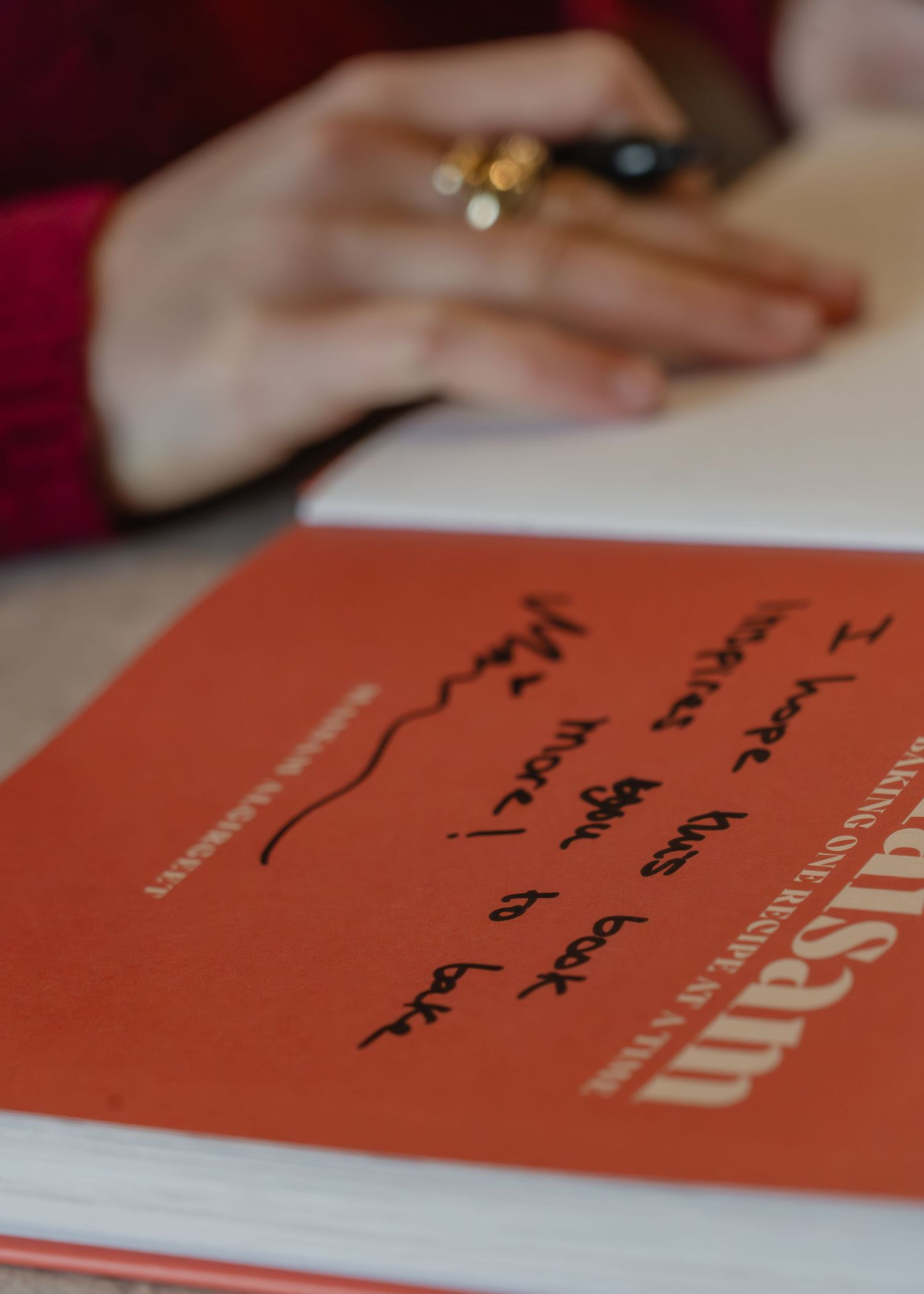 Orange book cover with handwritten text being photographed in sequence showing different pages and angles.