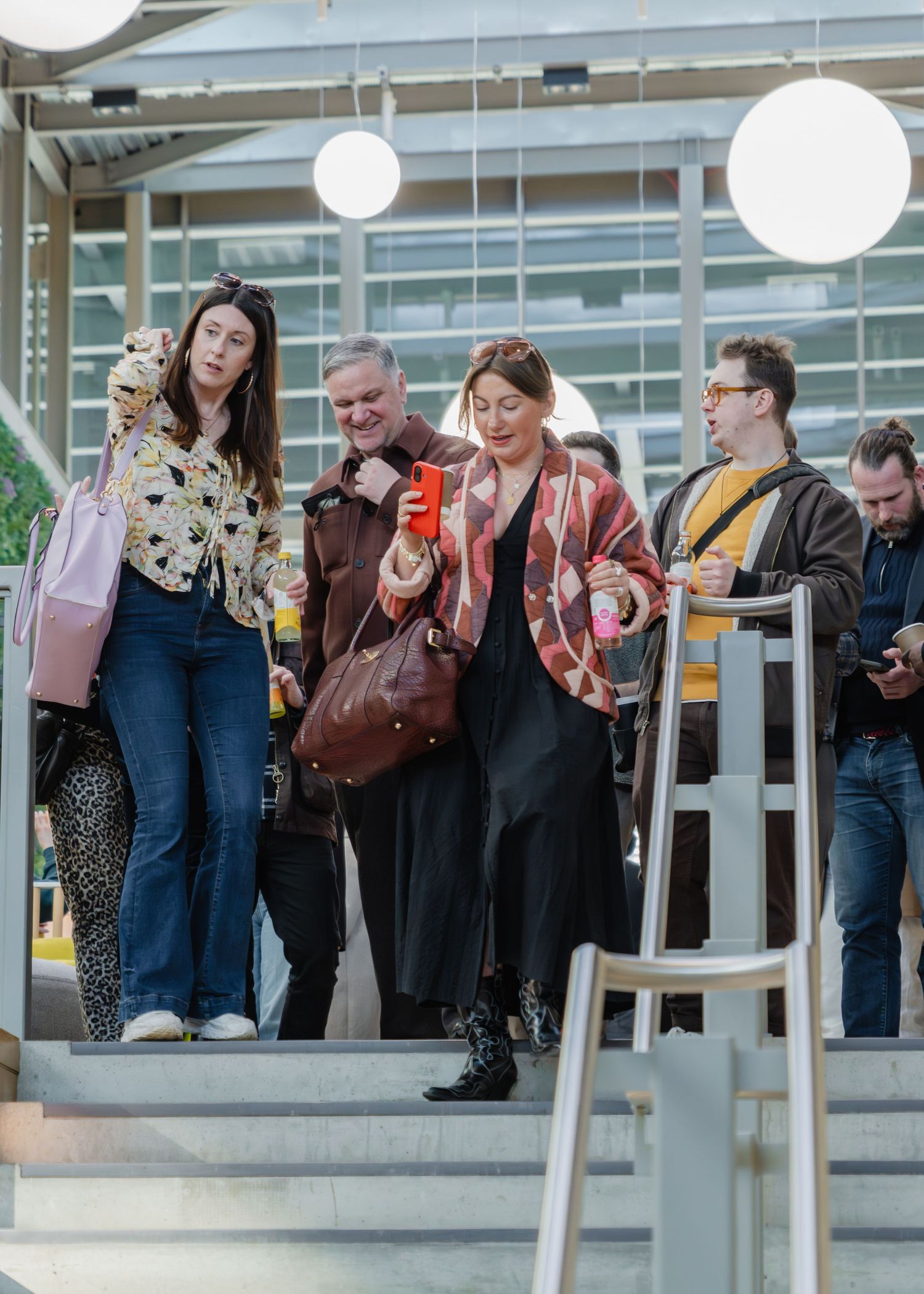A line of people standing at a modern airport security checkpoint with luggage and personal belongings.